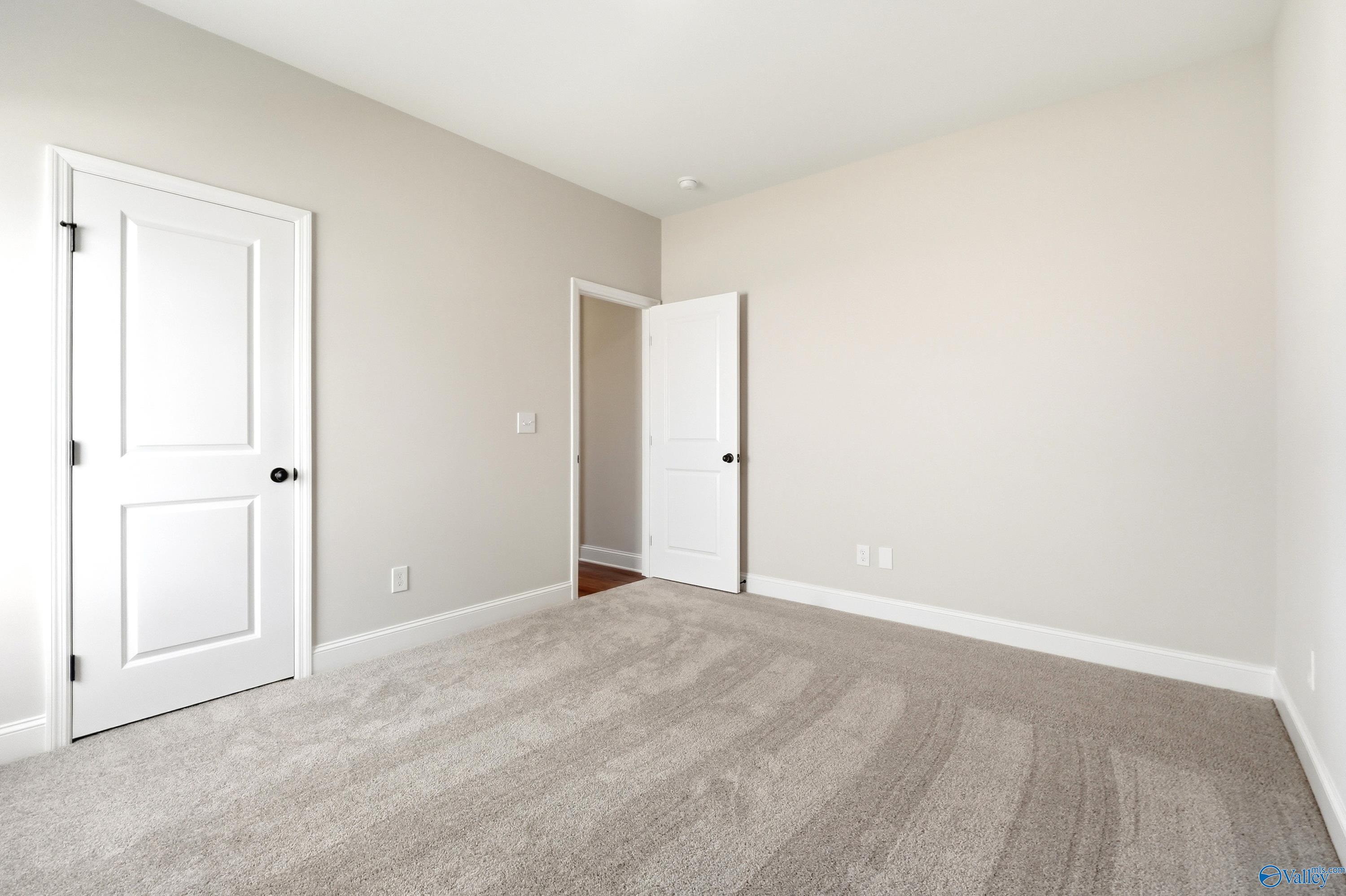 Spacious carpeted bedroom with neutral walls in The Daphne floor plan by Davidson Homes in Clearview, Hazel Green, Alabama.