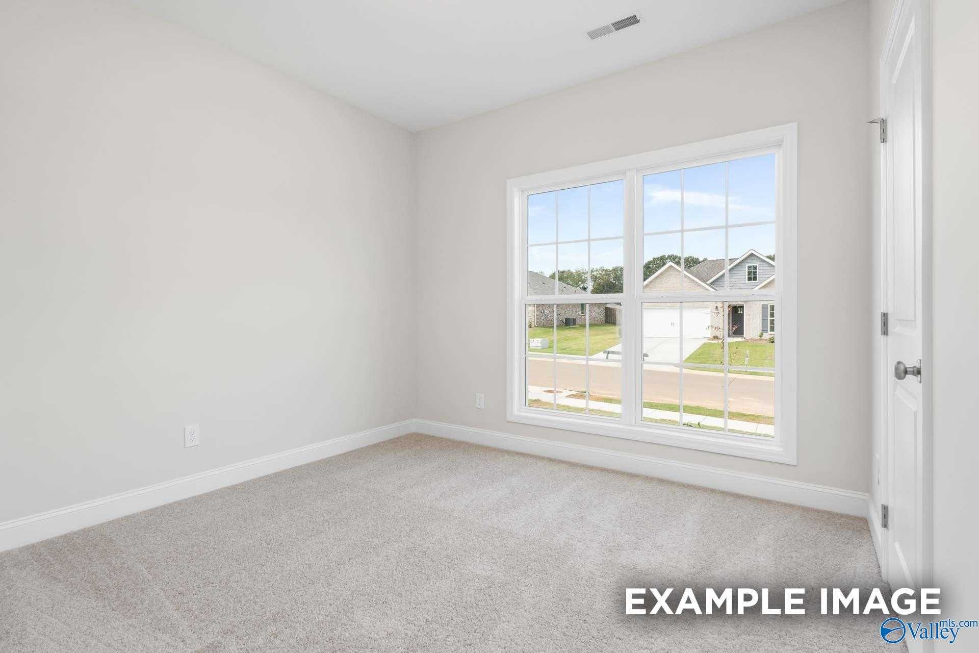 Bright bedroom with large window overlooking neighborhood in Davidson Homes The Franklin, Meridianville, Alabama
