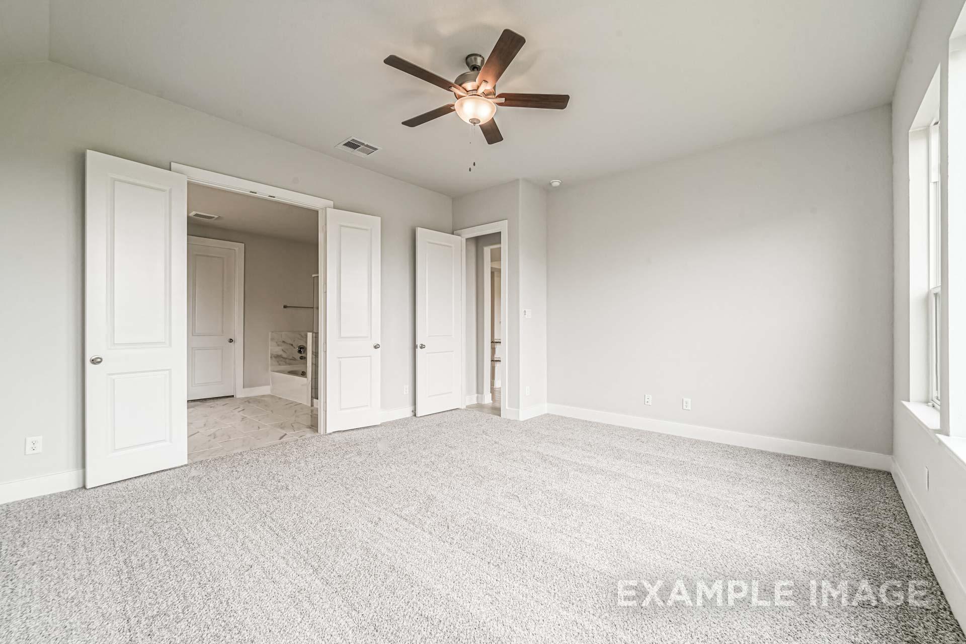 Spacious secondary bedroom in The George A Davidson Homes design with en-suite bath access, ceiling fan, and large windows