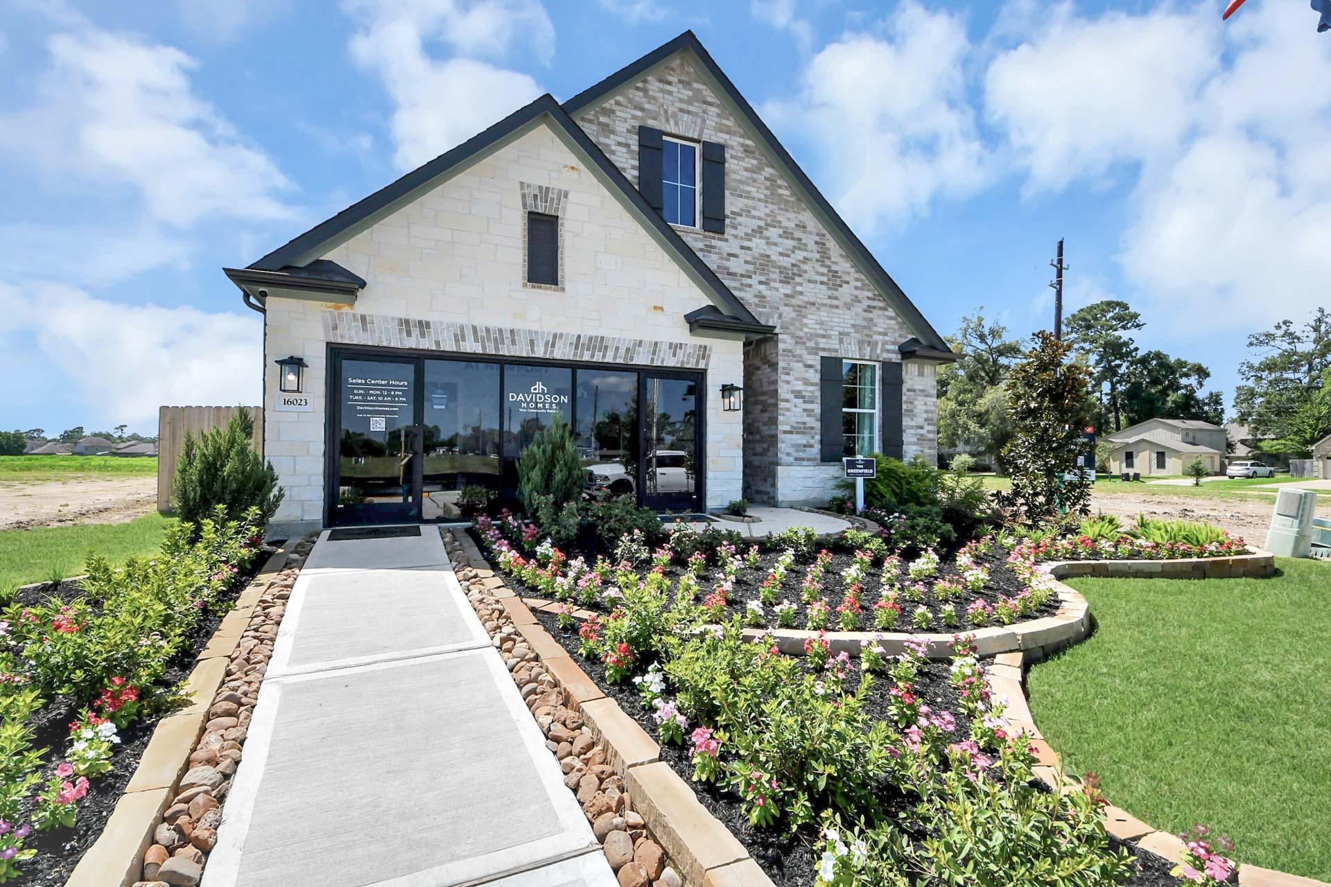 Davidson Homes sales center at Enclave at Newport in Crosby, Texas featuring stone exterior and landscaped flower beds.