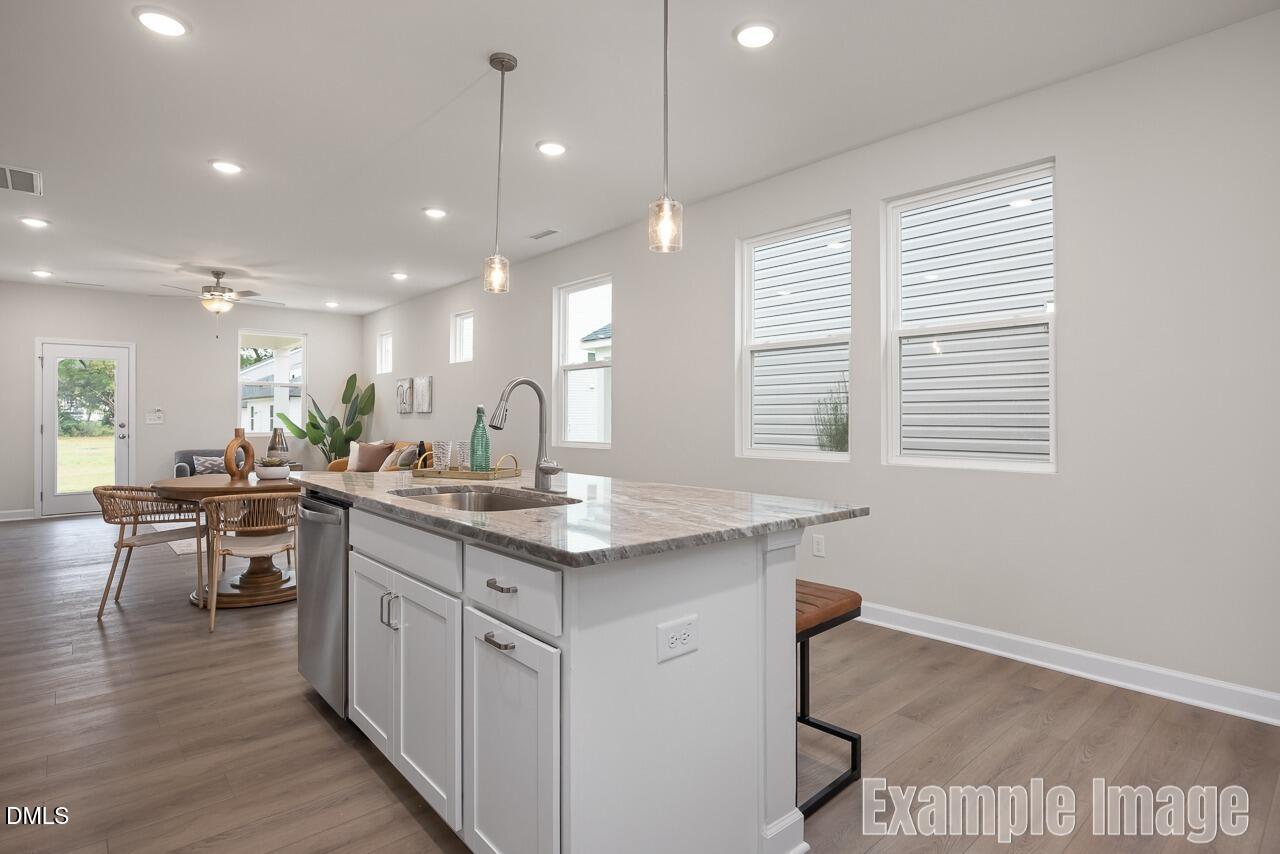 Modern open-concept kitchen with white cabinets, quartz island, and bar stools in Davidson Homes The Carter C, Lillington, NC