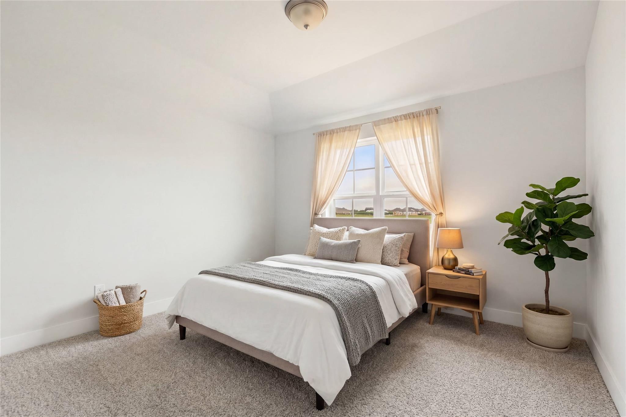 Bright secondary bedroom with white duvet bed, sheer-curtained window, and potted plant in Davidson Homes The Philip A, Lago Mar, Texas
