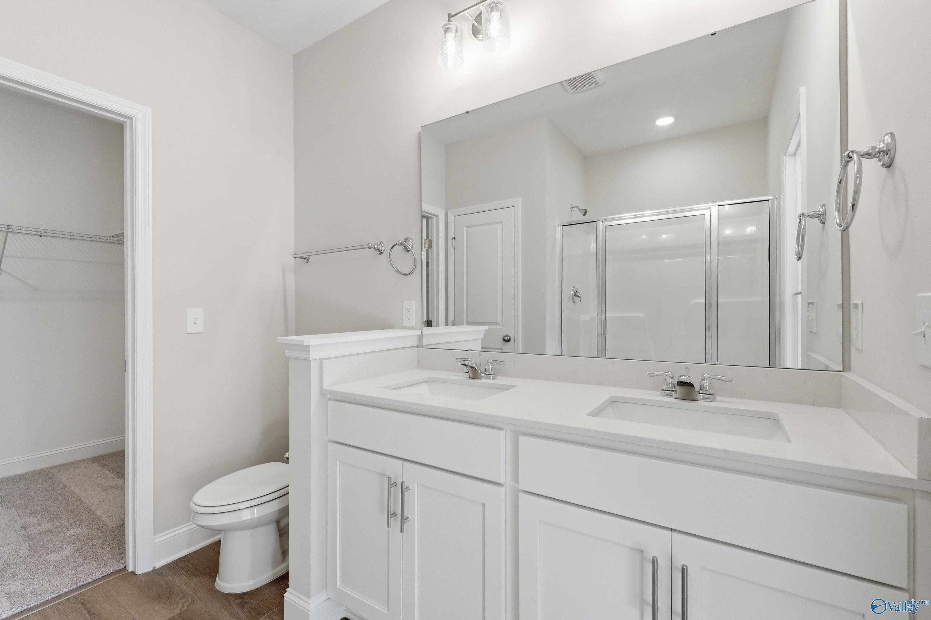 Modern master bathroom with double vanity, large mirror, glass shower, and walk-in closet in Davidson Homes The Asheville C, Huntsville, AL