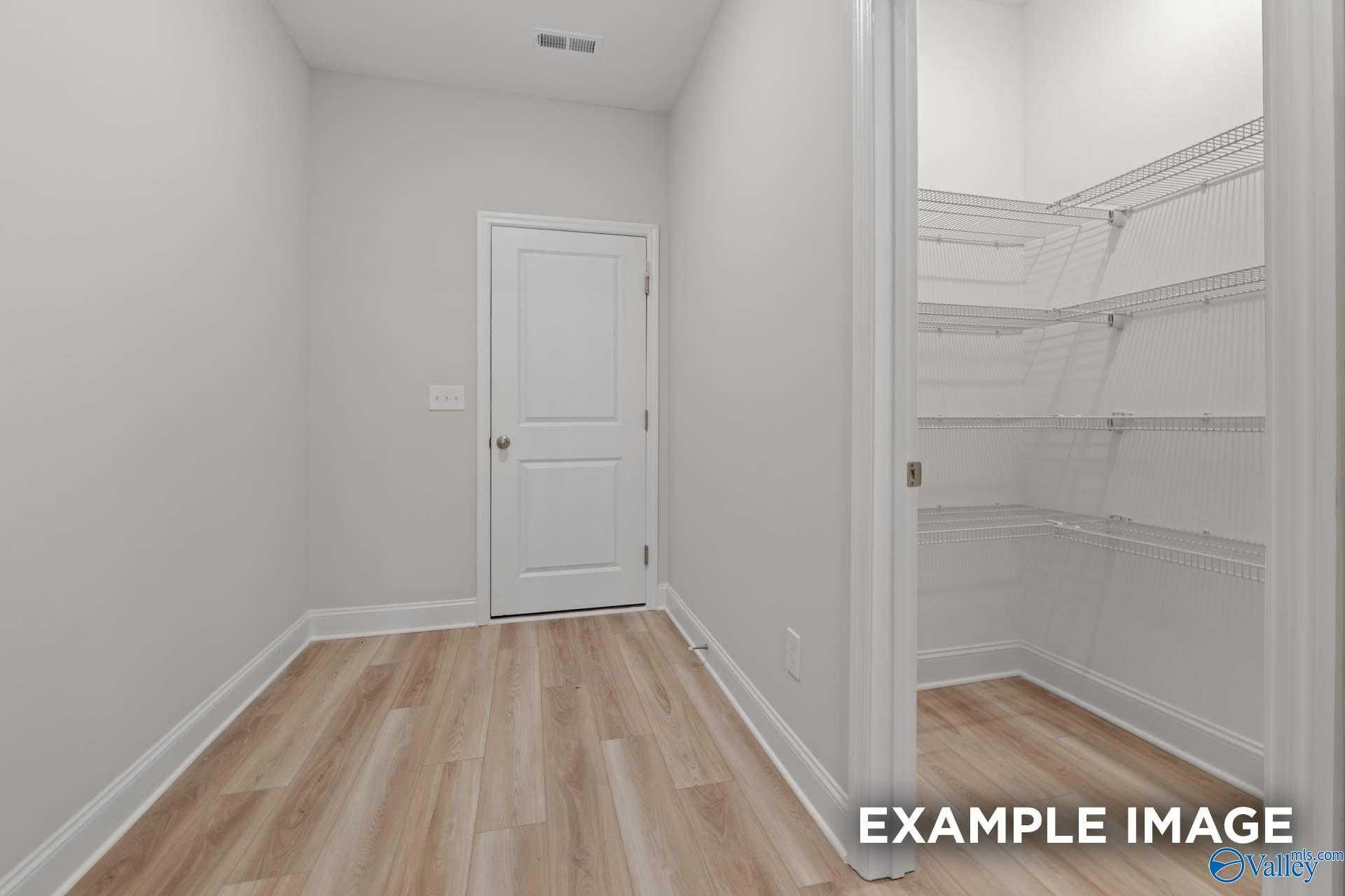 Spacious walk-in closet with wire shelving and laminate flooring in Davidson Homes The Camden, Huntsville, Alabama