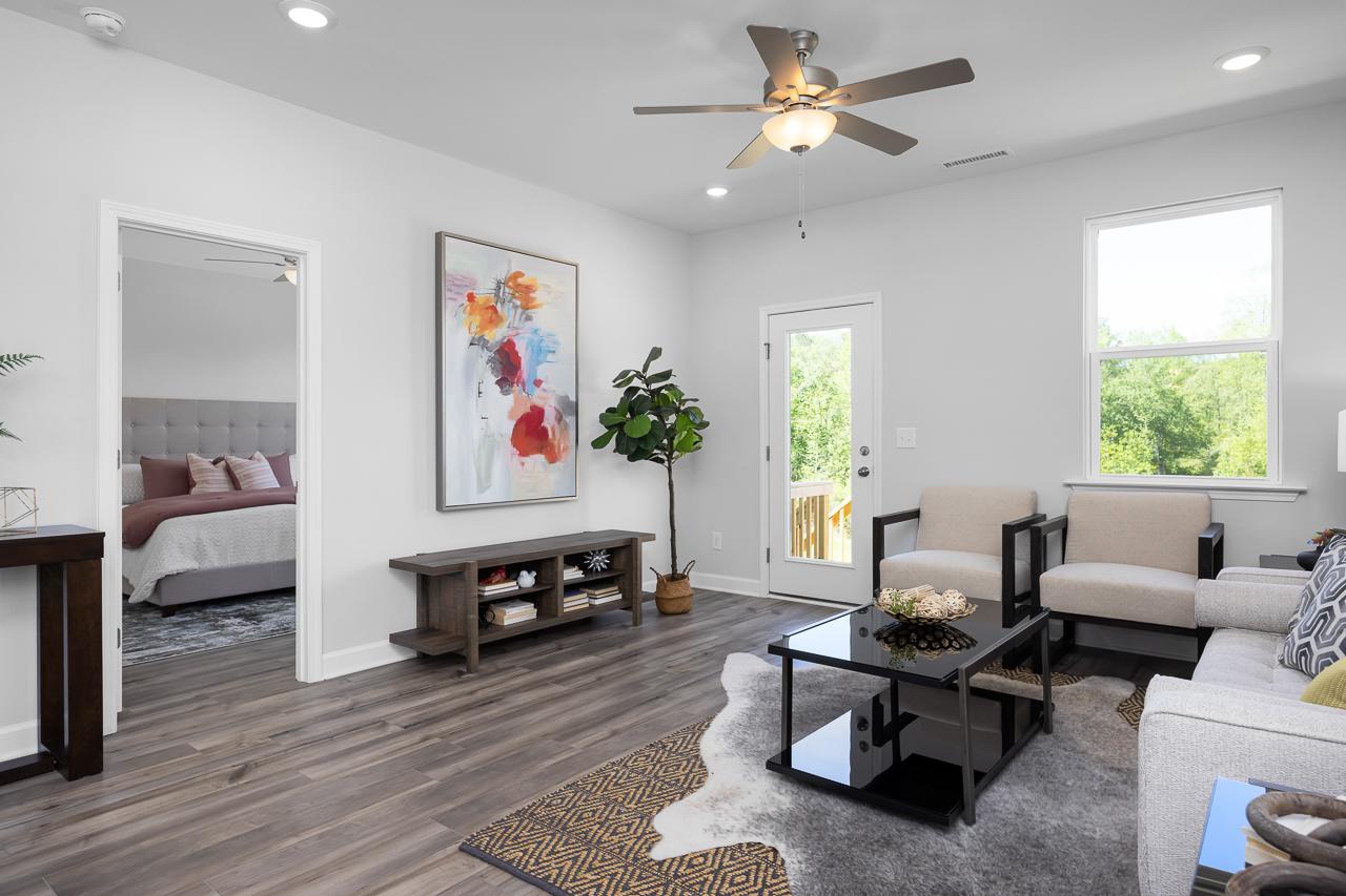 Spacious living room in Gregory Village Townhomes Lillington NC with hardwood floors, modern sofa, abstract art, and French doors to balcony
