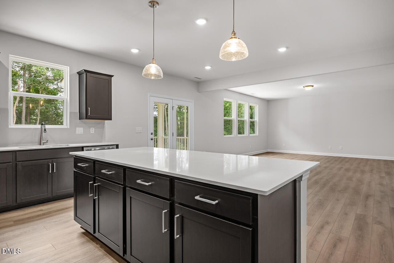 Modern kitchen with quartz island, dark cabinets, and open floor plan in The Hickory II B home in Wellers Knoll, Lillington.