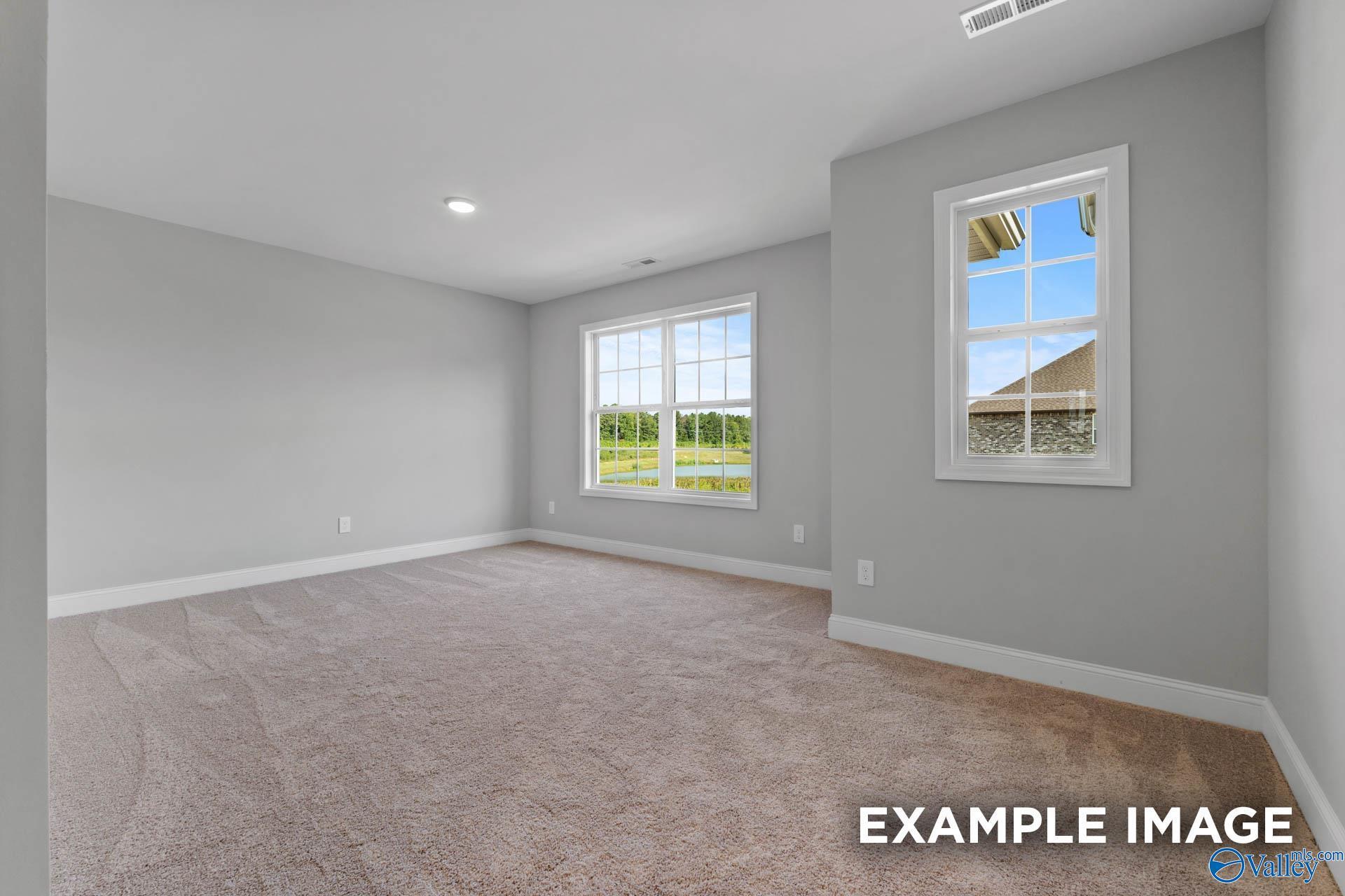 Bright, carpeted bedroom with large windows in The Shelby B floor plan by Davidson Homes in Walker's Hill, Meridianville.