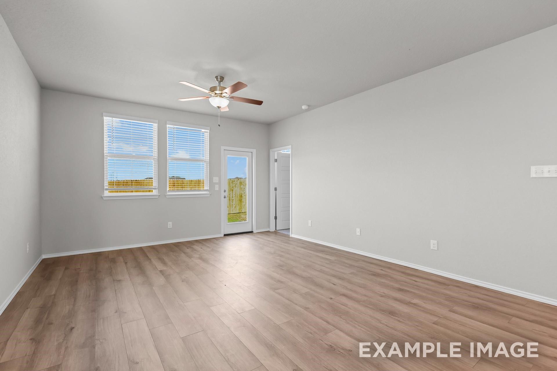 Spacious living area with wood-look flooring and ceiling fan in The Colorado G floor plan by Davidson Homes in Heartland, TX