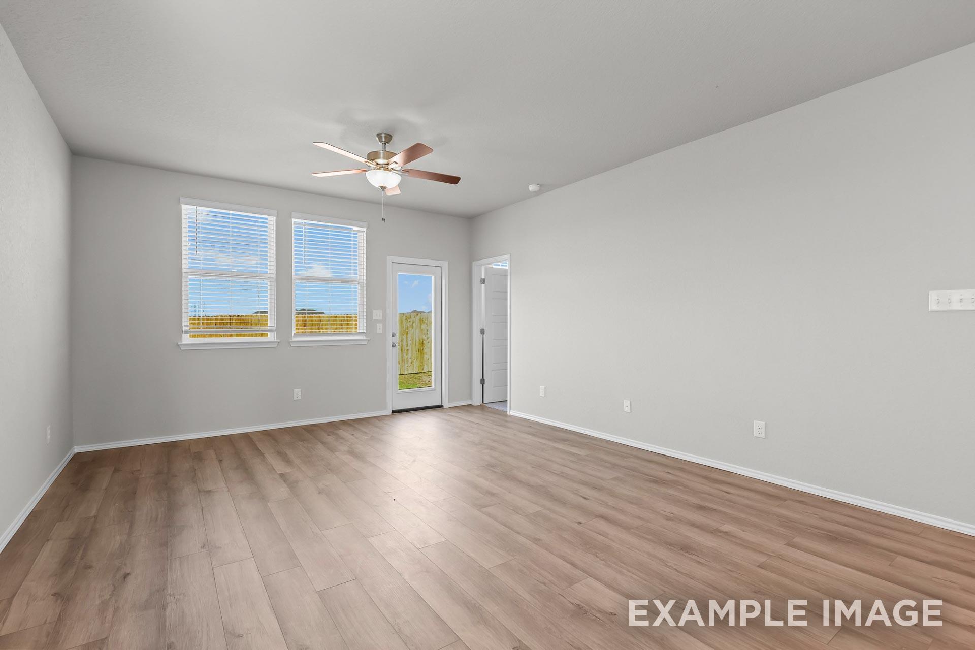 Spacious living area with wood-look flooring and ceiling fan in The Colorado G floor plan by Davidson Homes in Heartland, TX