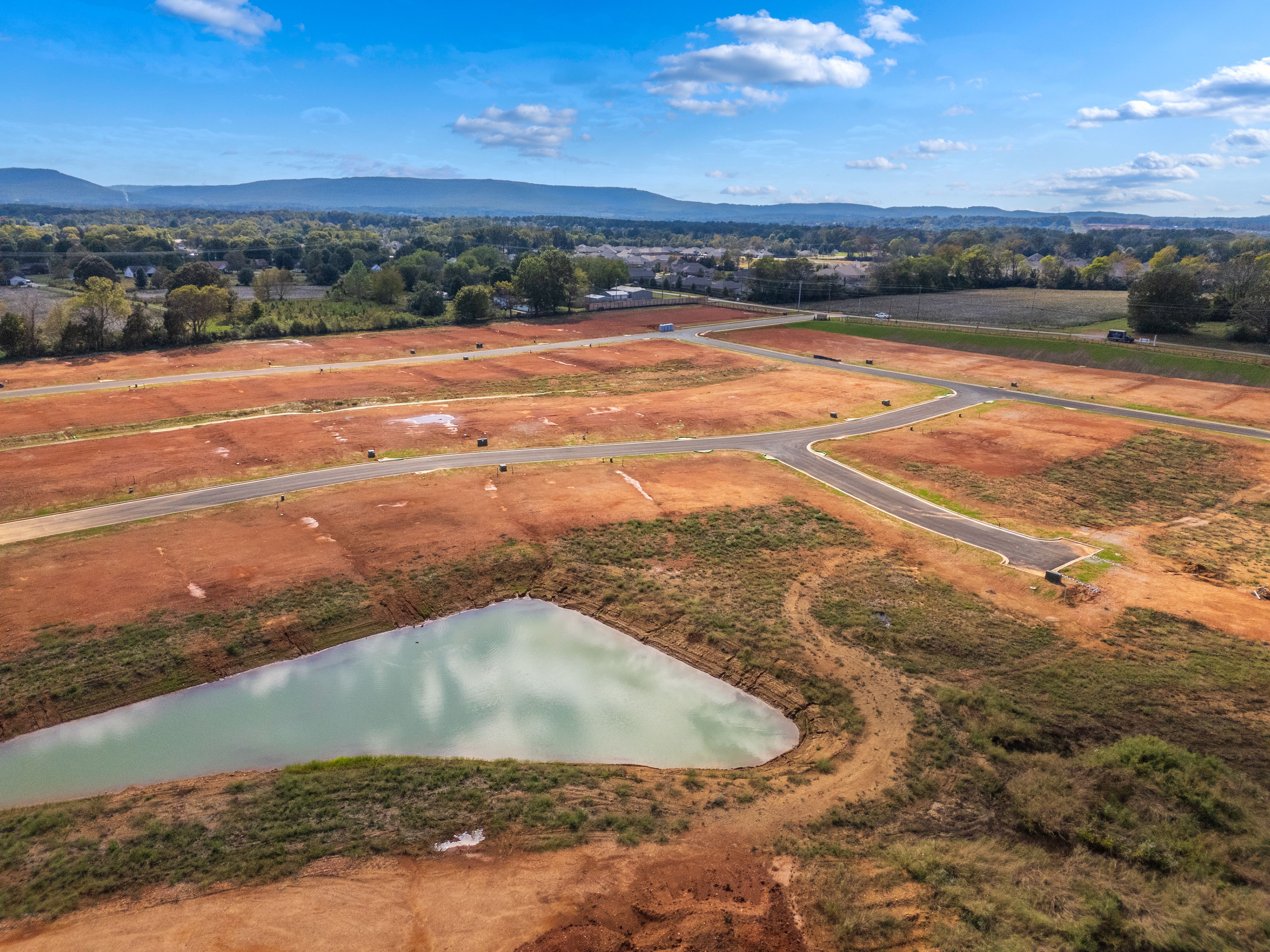 Aerial view of Berry Cove development in New Market Alabama featuring red dirt lots roads and pond by Davidson Homes