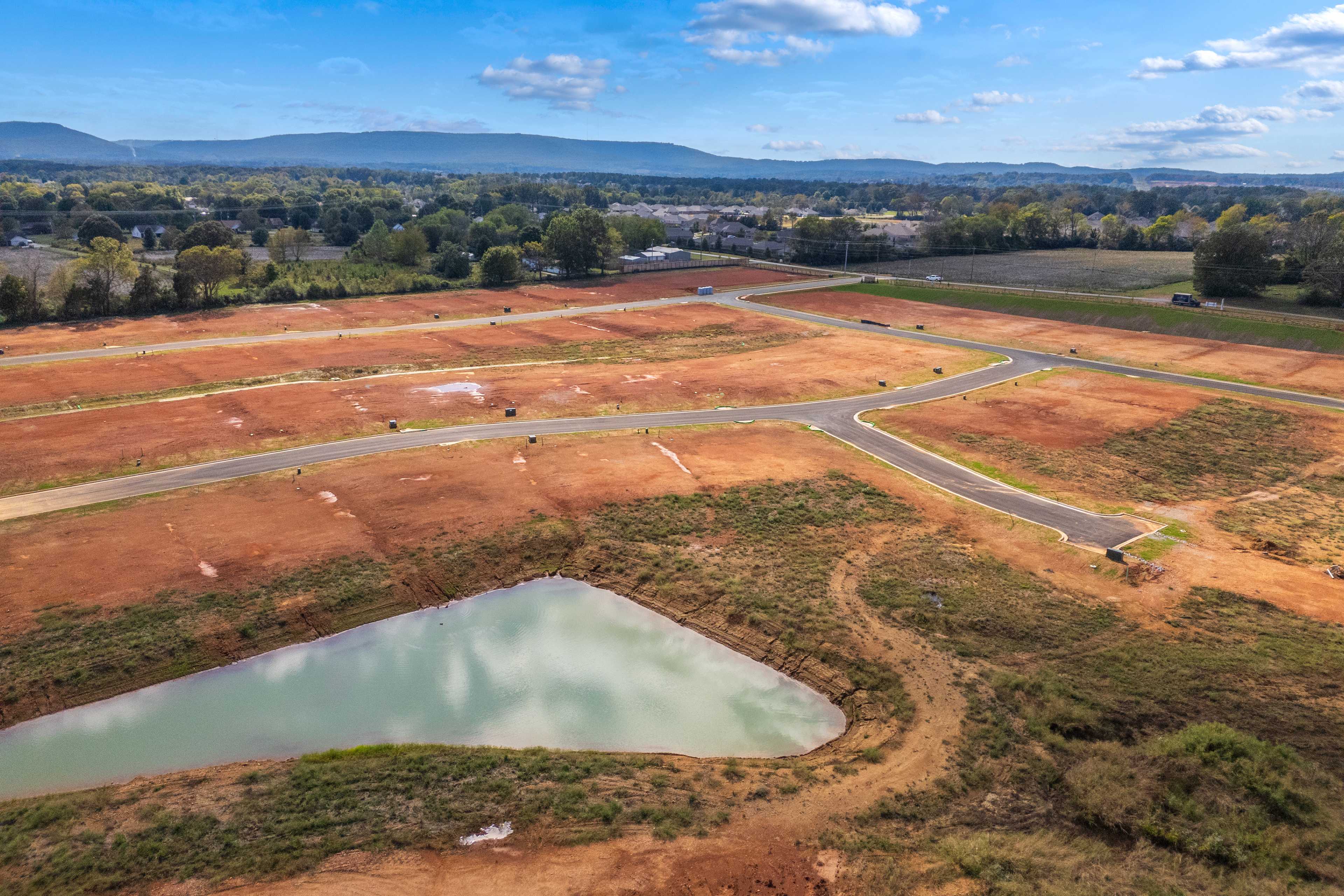 Aerial view of Berry Cove development in New Market Alabama featuring red dirt lots roads and pond by Davidson Homes
