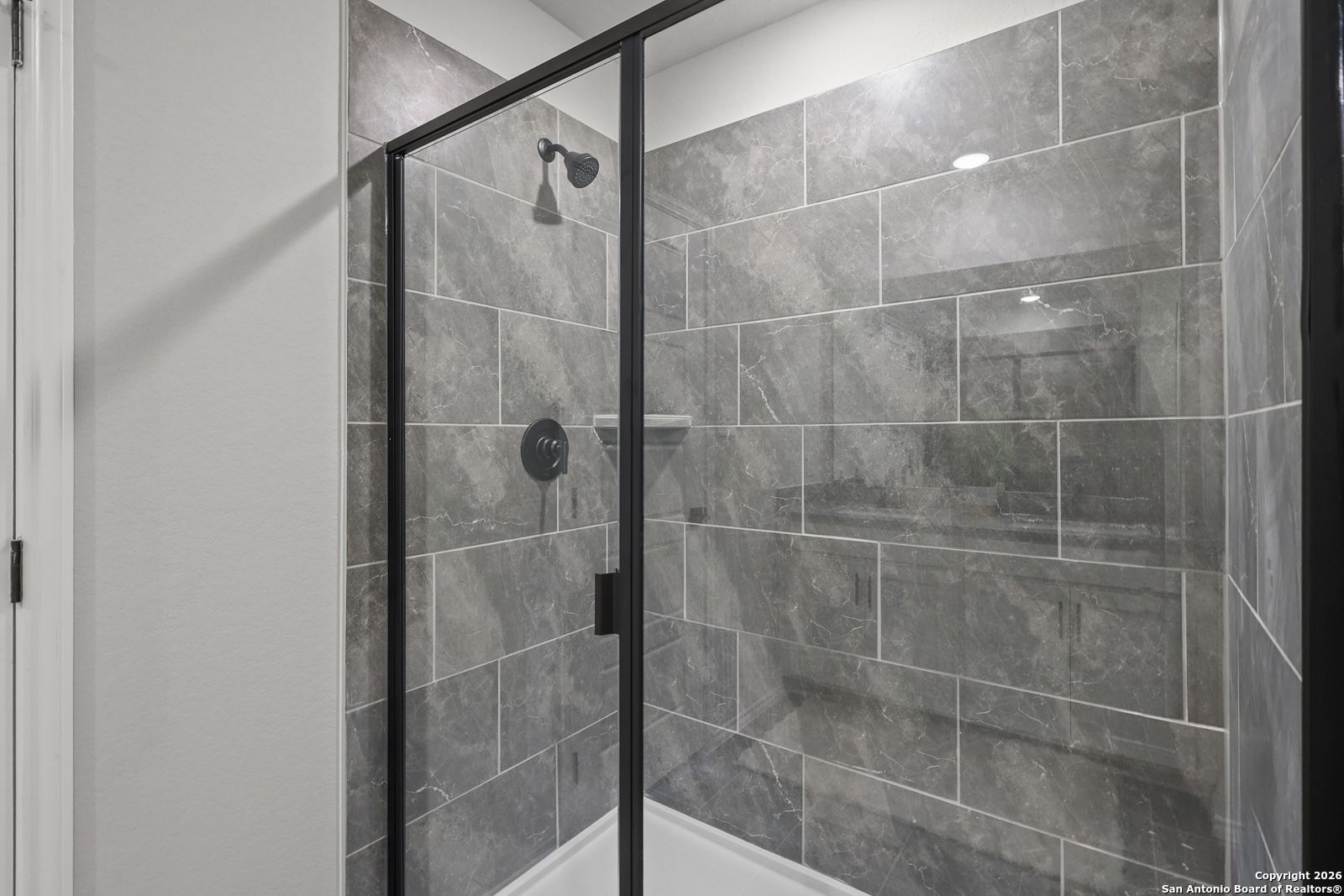 Modern frameless glass shower with gray subway tiles and niche shelf in master bath, Davidson Homes The Murray K, San Antonio