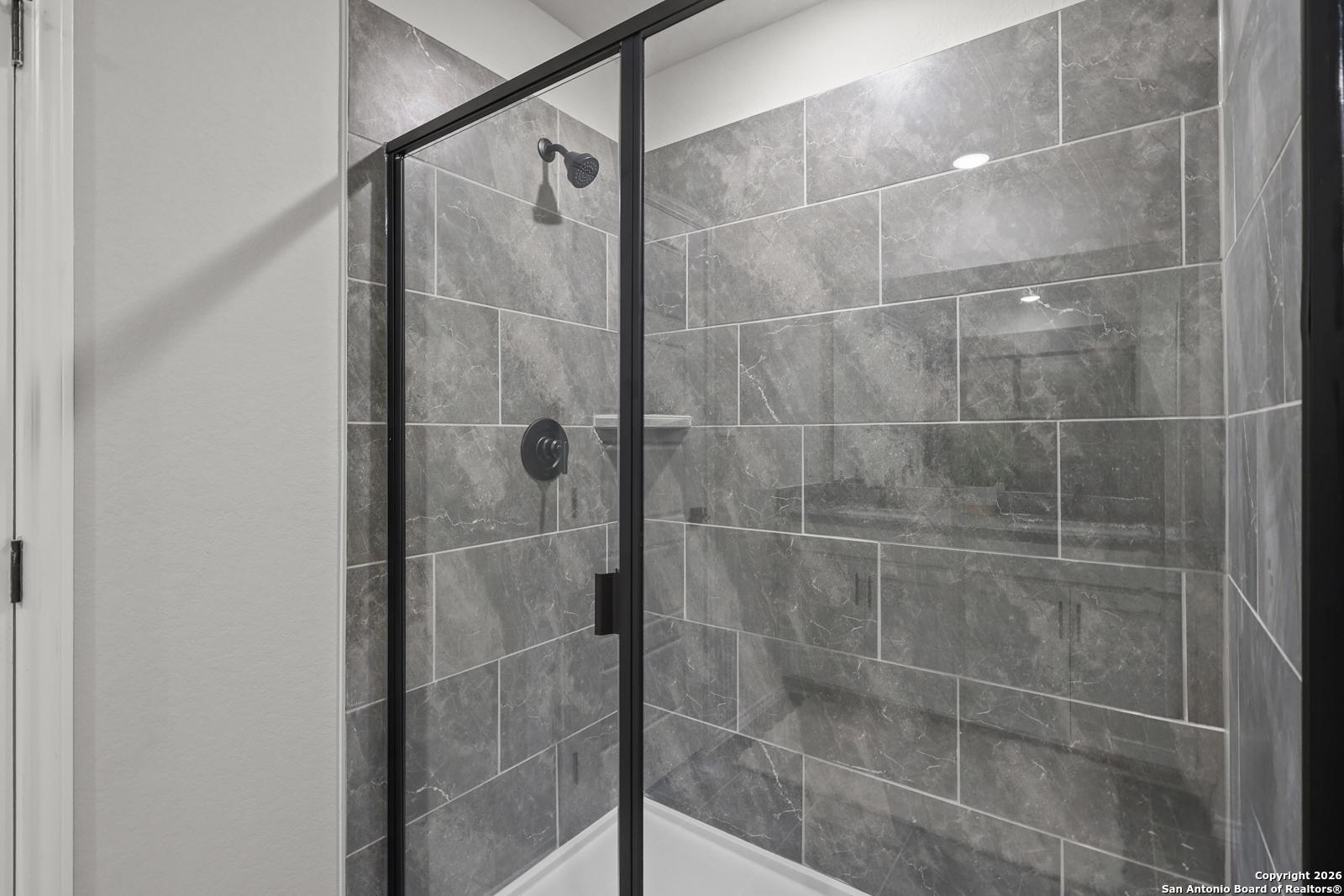 Modern frameless glass shower with gray subway tiles and niche shelf in master bath, Davidson Homes The Murray K, San Antonio