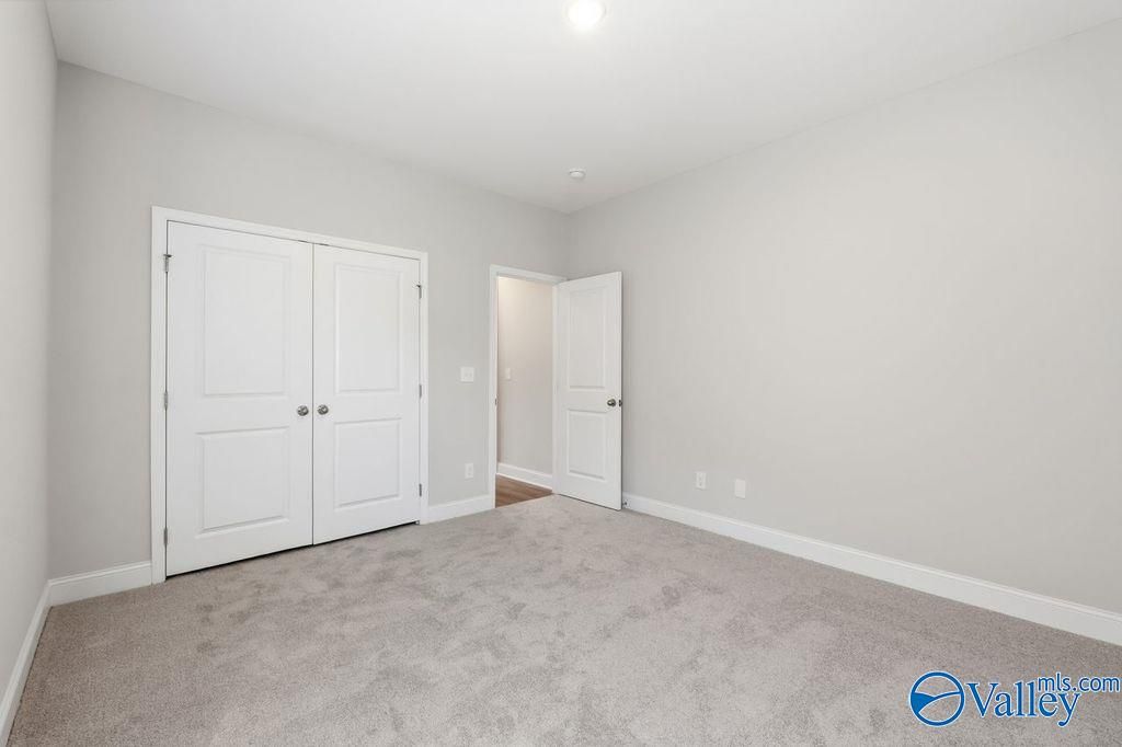 Spacious bedroom with double white closet doors and open bathroom entry in Davidson Homes The Harrison, Hartselle Alabama
