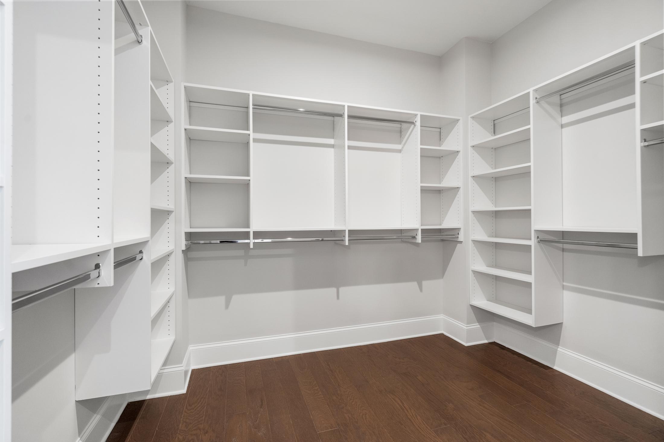 Spacious walk-in closet in The Seaside A master suite with white built-in shelving, hanging rods, and hardwood floors