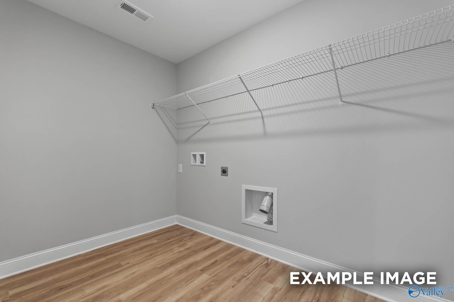 Functional laundry room with wire shelving, utility sink, washer/dryer hookups and hardwood floors in Davidson Homes The Shelby B, New Market, Alabama