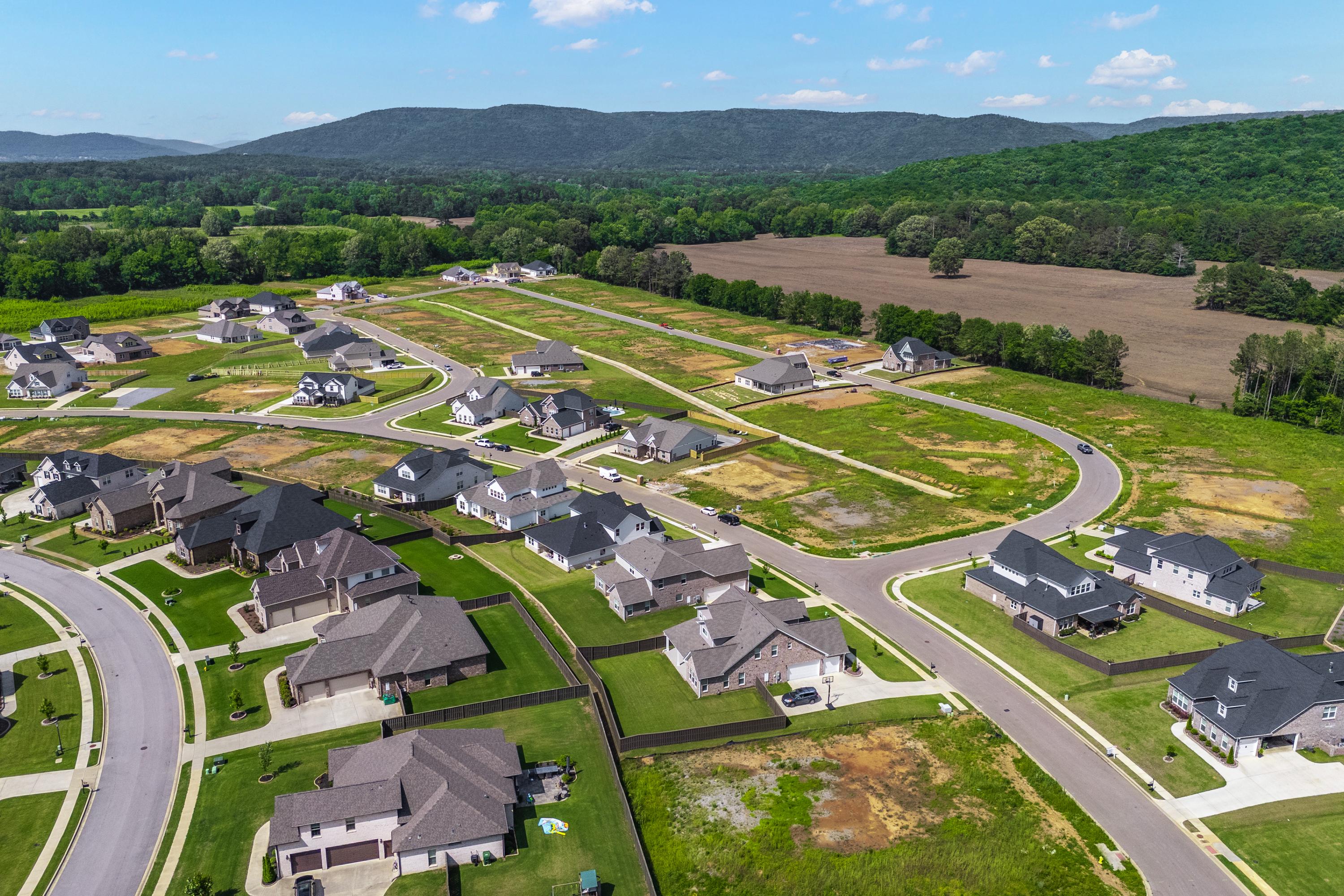 Aerial view of modern homes in The Meadows at Hampton Cove, Owens Cross Roads Alabama with winding streets, green lots and mountain backdrop