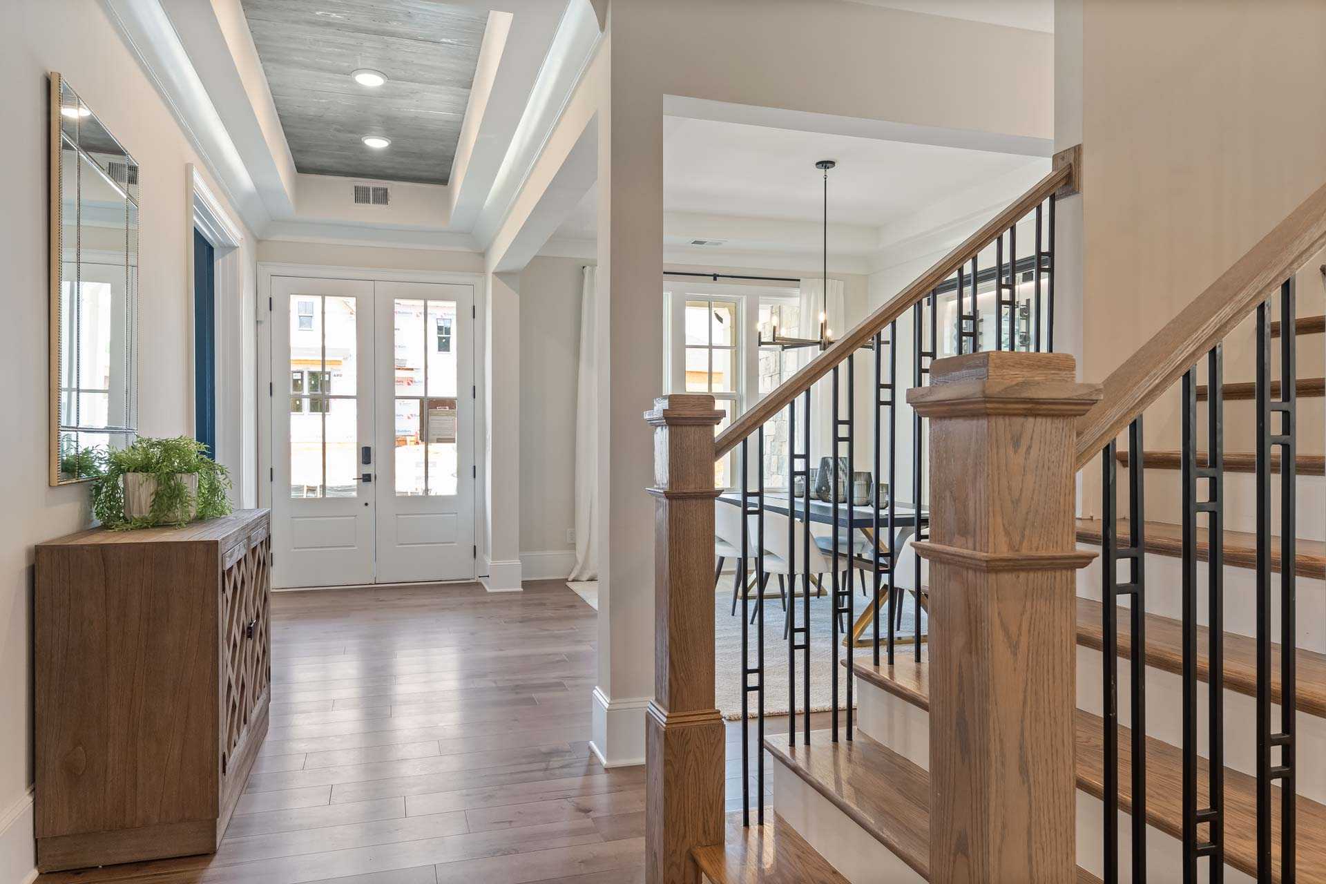 Elegant foyer in Tanglewood East Cobb Georgia home by Davidson Homes featuring oak staircase black metal railing and hardwood floors