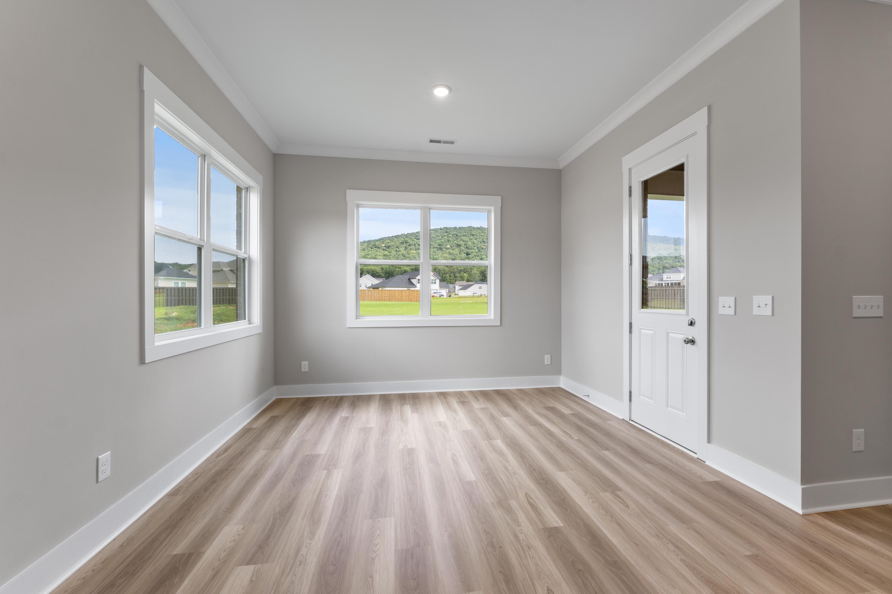 Spacious master suite in The Oxford C home with large windows overlooking countryside, hardwood floors, gray walls