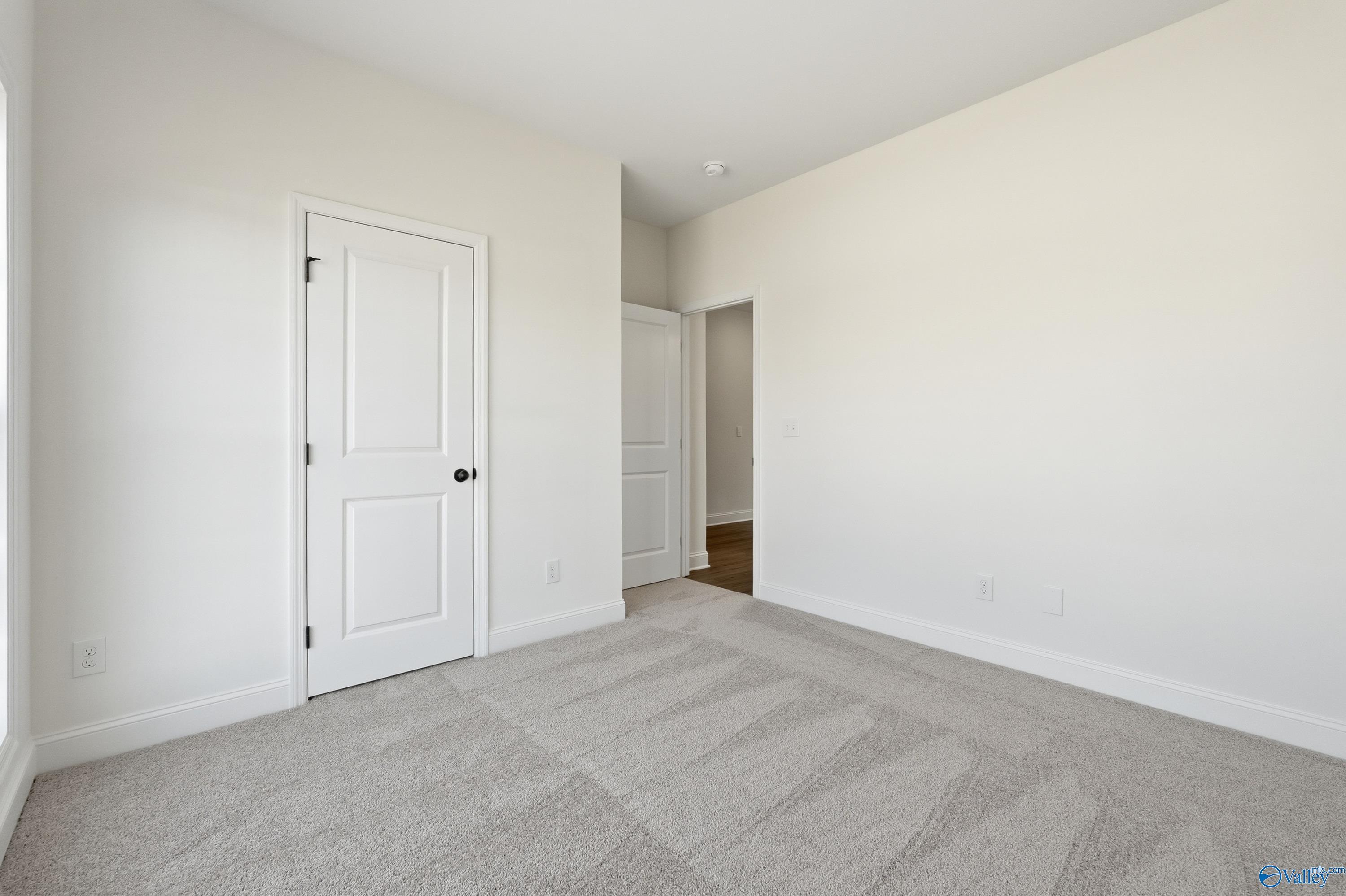 Empty secondary bedroom with beige carpet, white walls, and double doors in Davidson Homes The Franklin C, New Market, Alabama