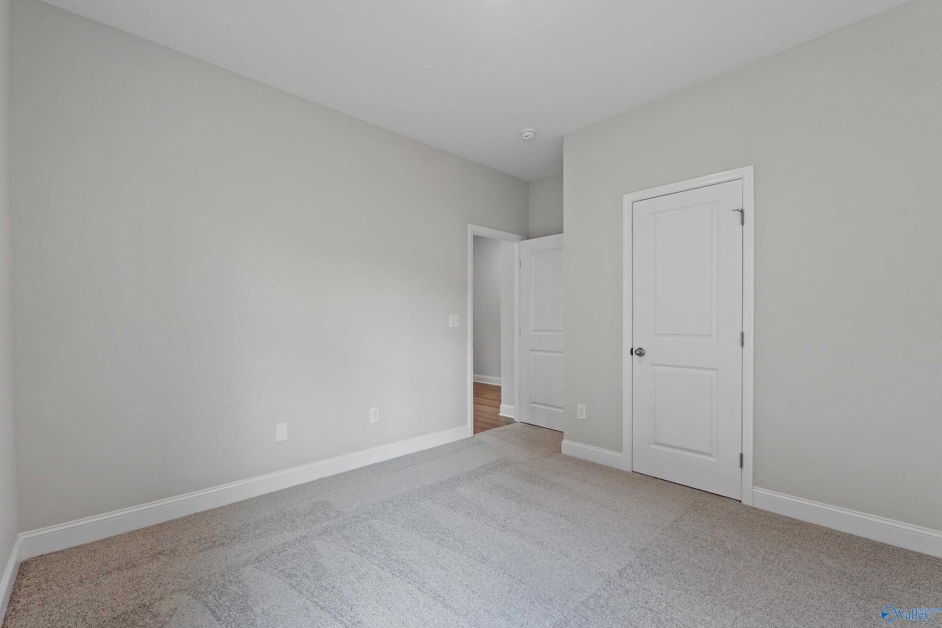 Neutral secondary bedroom with light gray walls, beige carpet, and white doors in Davidson Homes The Franklin C, Harvest, Alabama