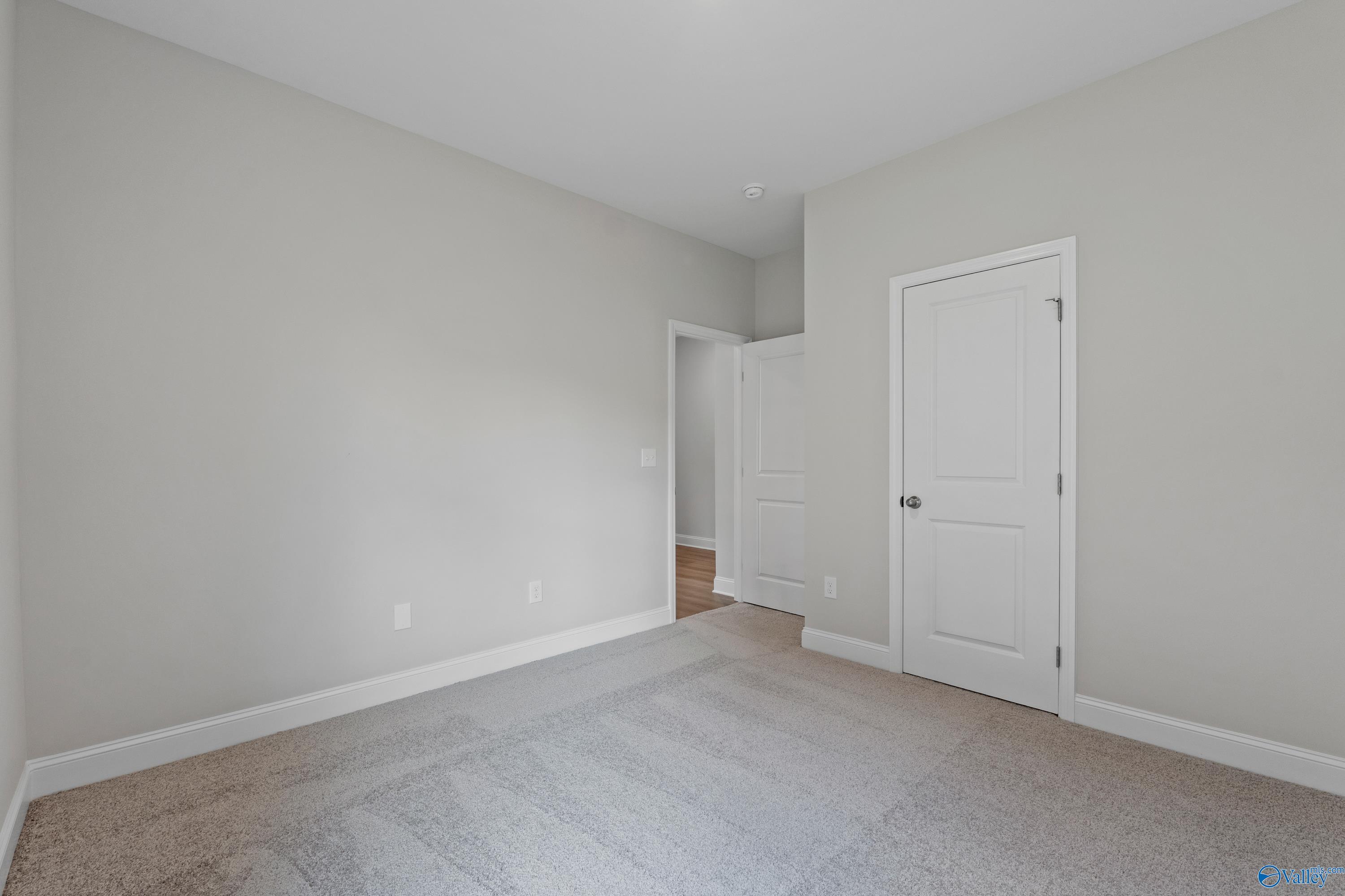 Neutral secondary bedroom with light gray walls, beige carpet, and white doors in Davidson Homes The Franklin C, Harvest, Alabama