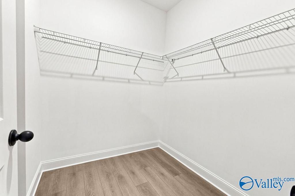 Walk-in closet with wire shelving and wood-look flooring in The Camilla B floor plan at The Retreat at Cain Park, Hartselle.