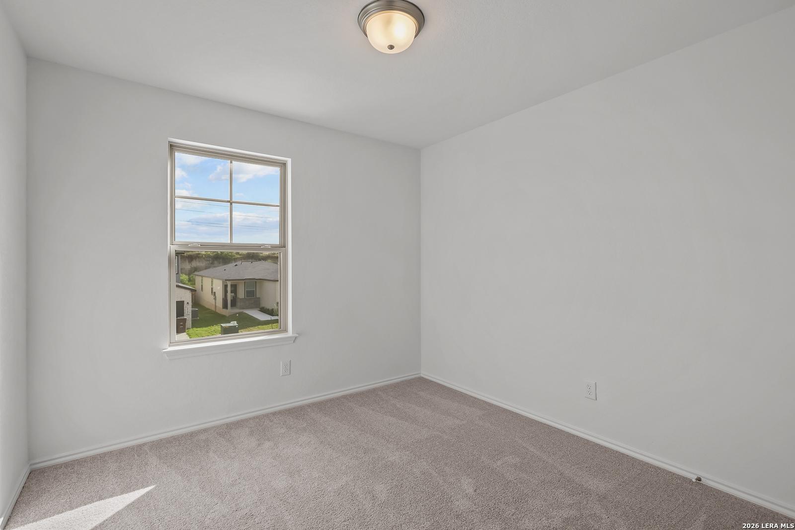 Bright, carpeted bedroom with neutral walls in The Brazos B floor plan by Davidson Homes in Agave, San Antonio, Texas.