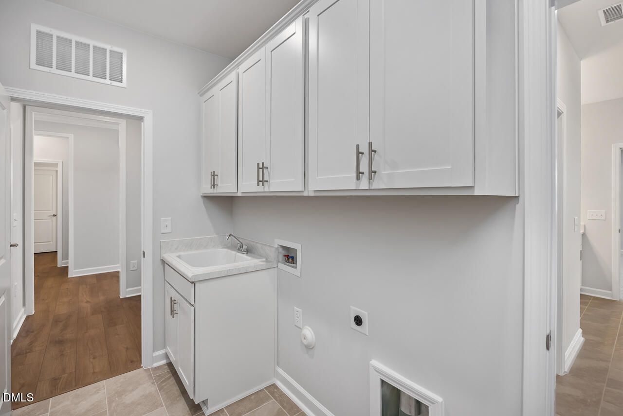 Laundry room with white cabinets and utility sink in The Ashport L floor plan at Sage on North Main, Wake Forest, NC.