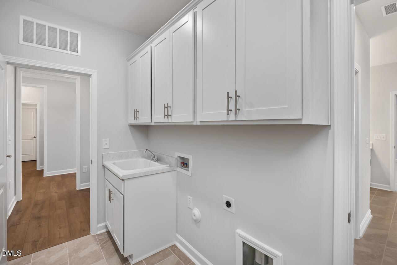 Laundry room with white cabinets and utility sink in The Ashport L floor plan at Sage on North Main, Wake Forest, NC.