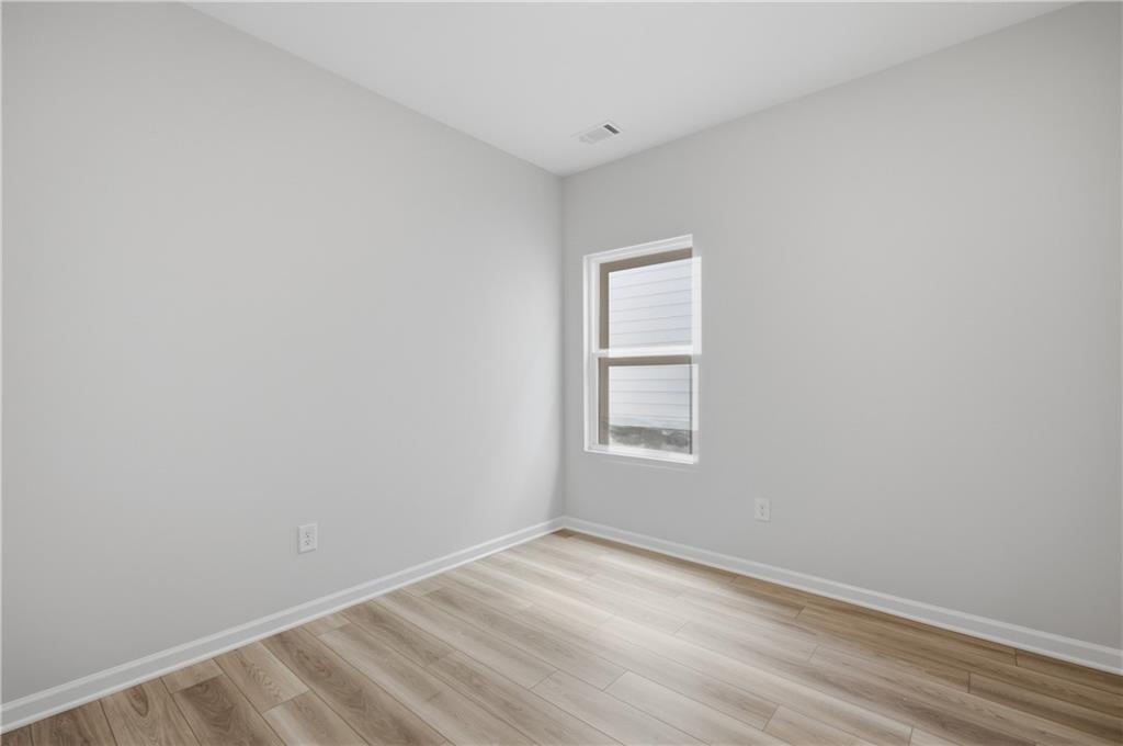 Bright empty bedroom with luxury vinyl plank flooring and window in Davidson Homes' Oconee B plan at The Bluffs, Canton, GA