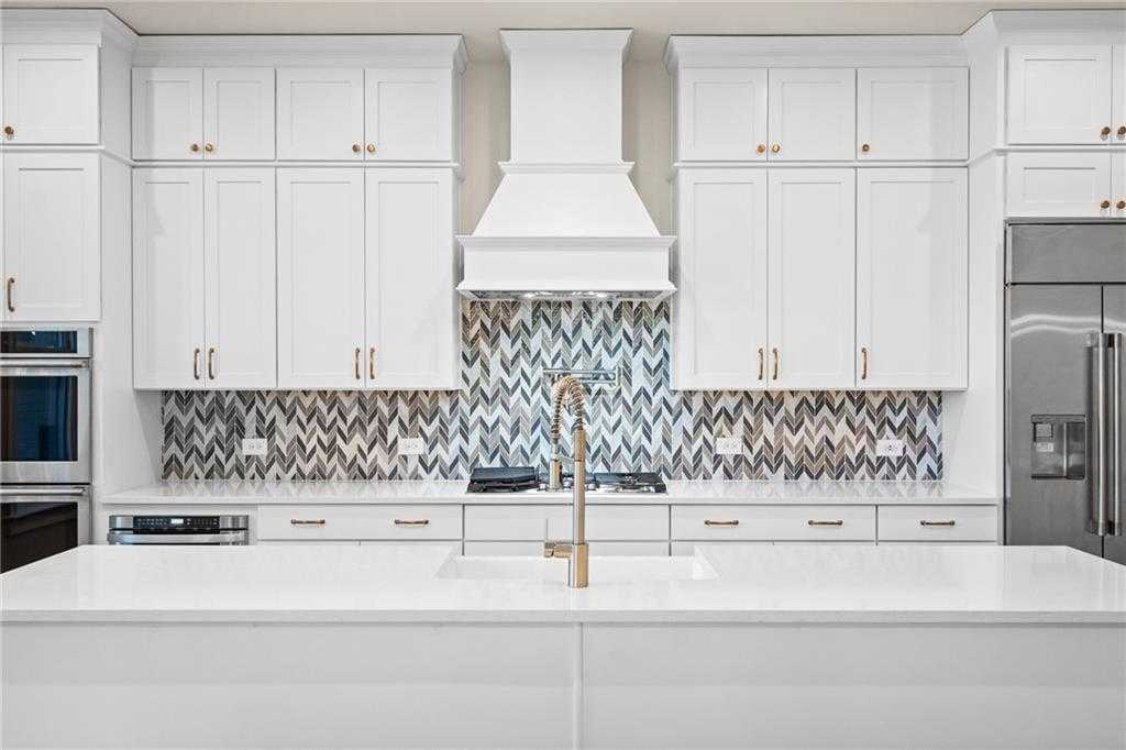 Modern white kitchen with shaker cabinets, quartz island, stainless appliances, chevron backsplash in Davidson Homes The Arlington A, East Cobb, GA