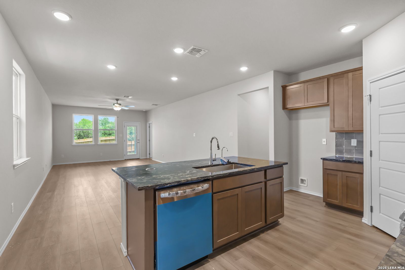 Open-concept kitchen with dark countertops and wood cabinets in The San Marcos F floor plan, Rayburn Valley, San Antonio.