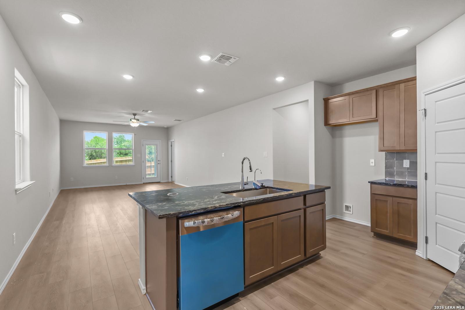 Open-concept kitchen with dark countertops and wood cabinets in The San Marcos F floor plan, Rayburn Valley, San Antonio.