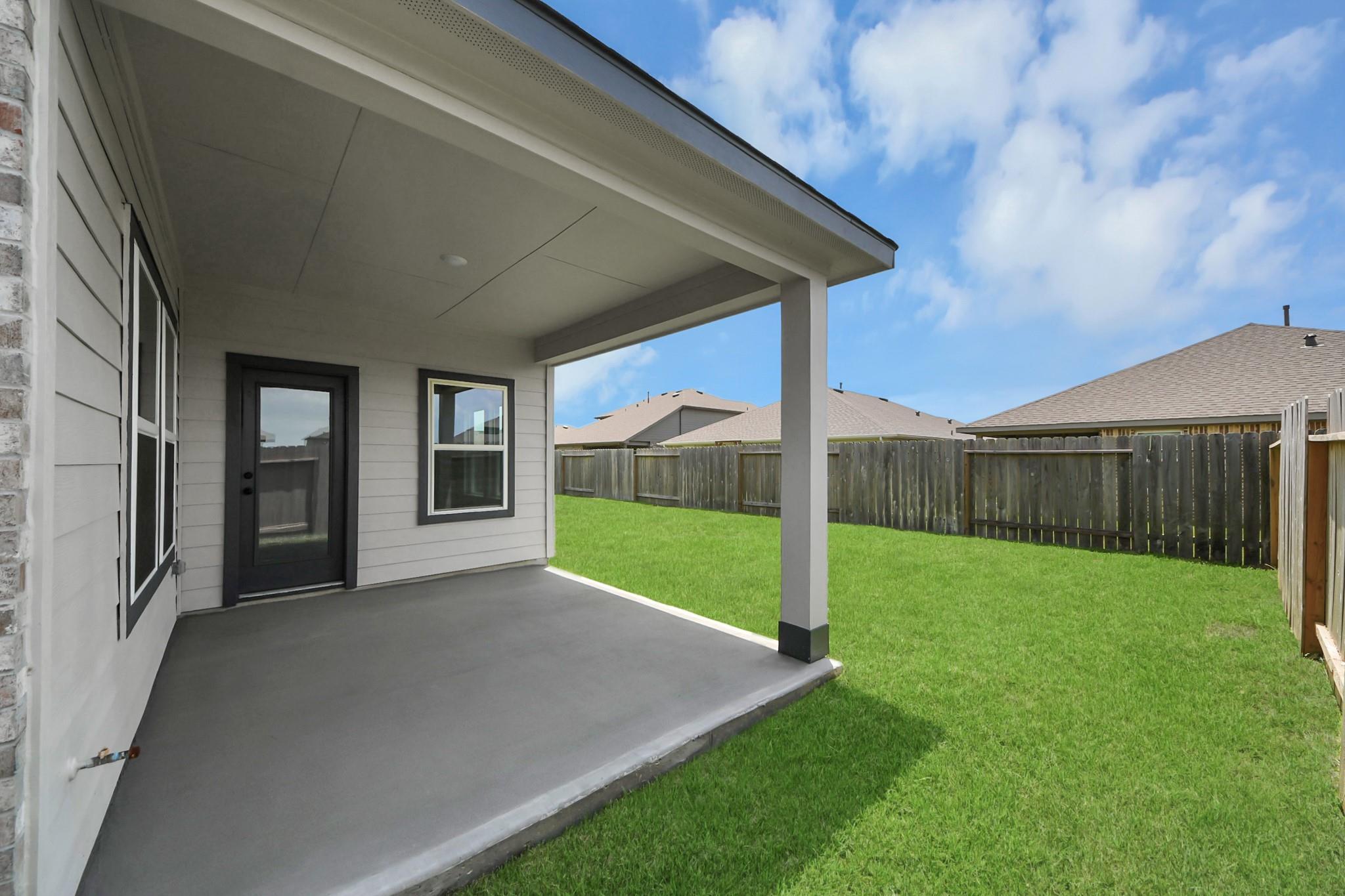 Covered concrete patio overlooking a private fenced backyard at The Everett C floor plan in River Ranch Meadows, Dayton, TX.