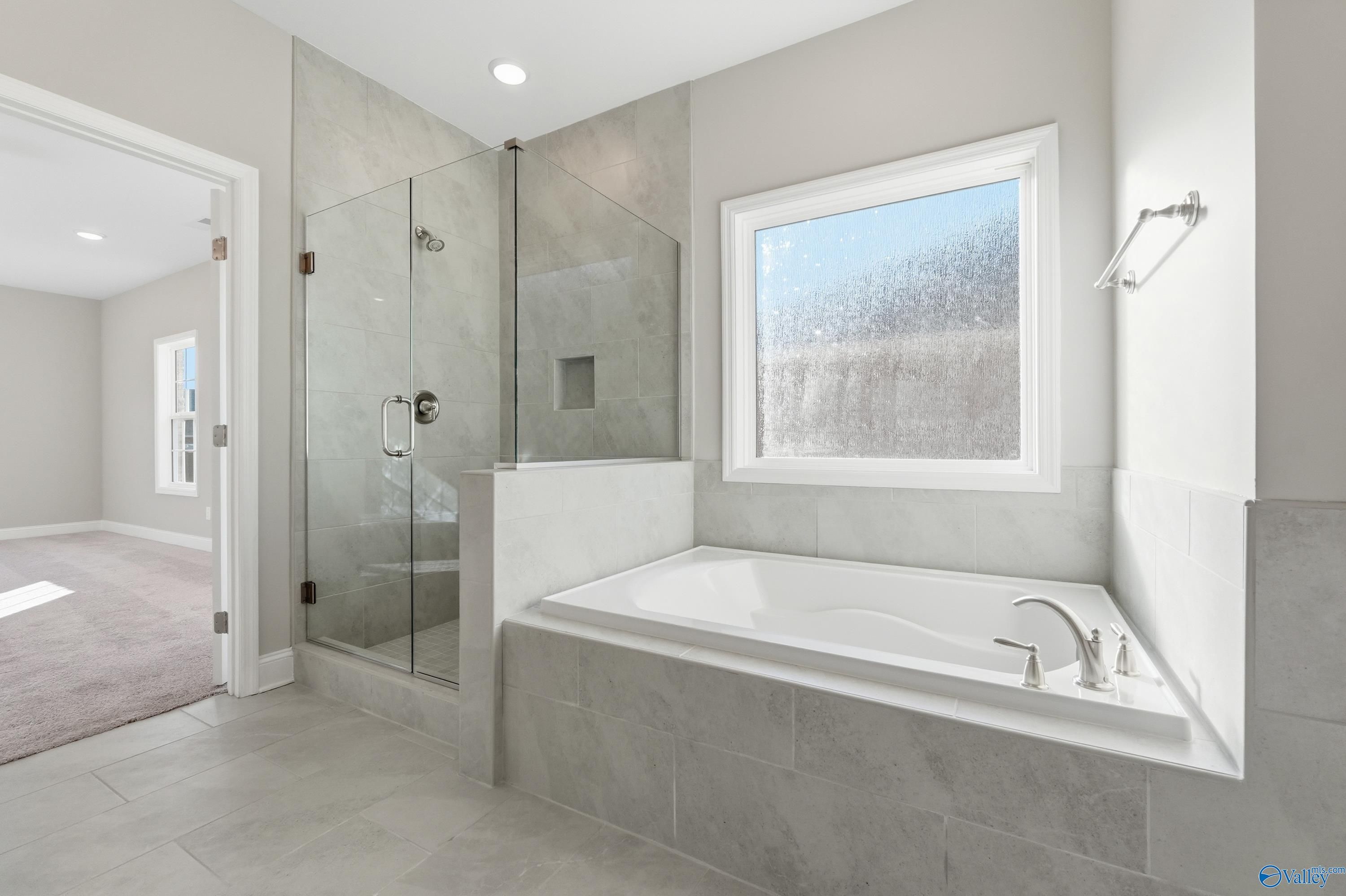 Modern master bathroom featuring frameless glass shower and soaking tub in Davidson Homes The Lanier, Toney, Alabama