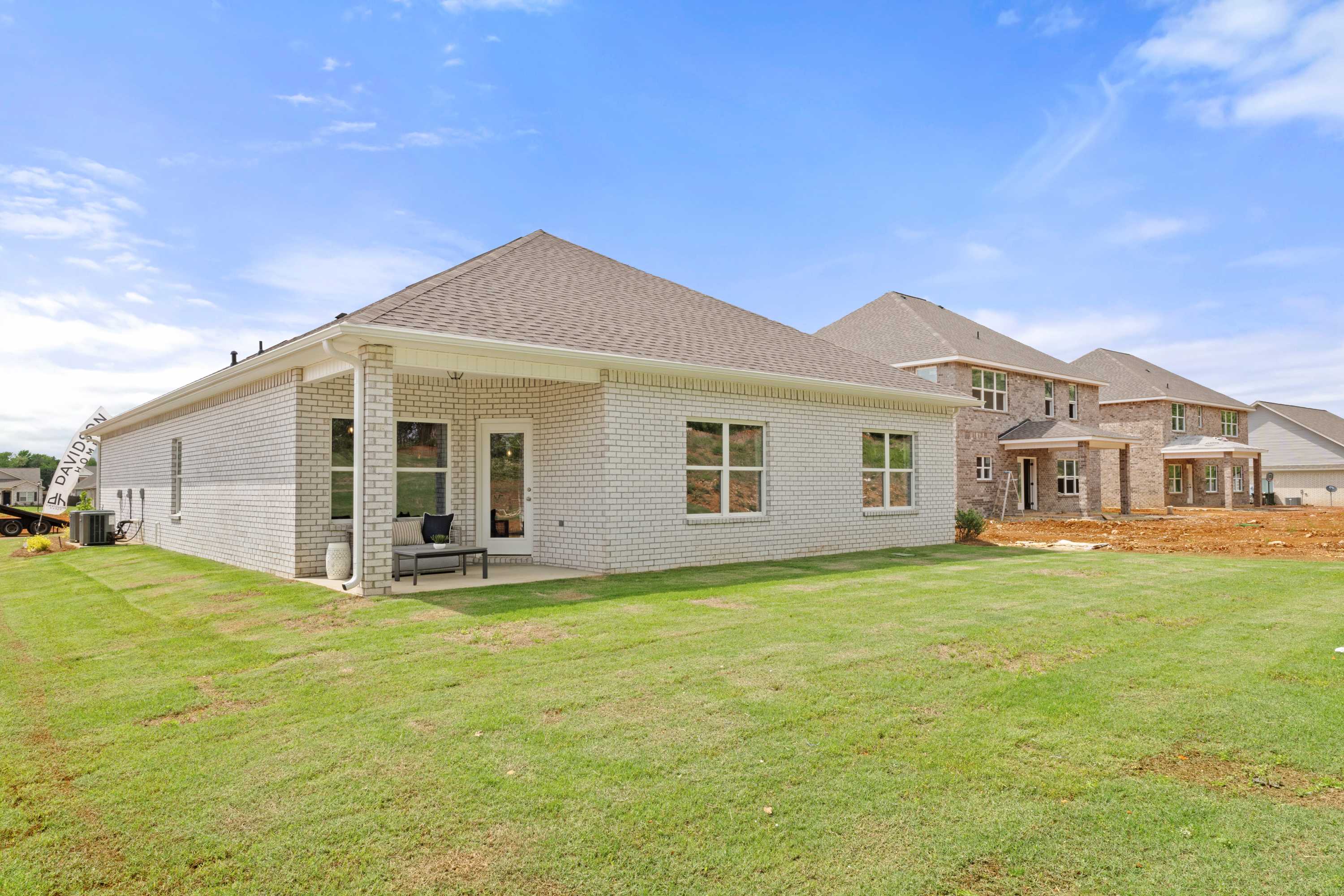 Brick home side exterior at Ivy Hills in Toney Alabama with covered patio, white columns, and green lawn