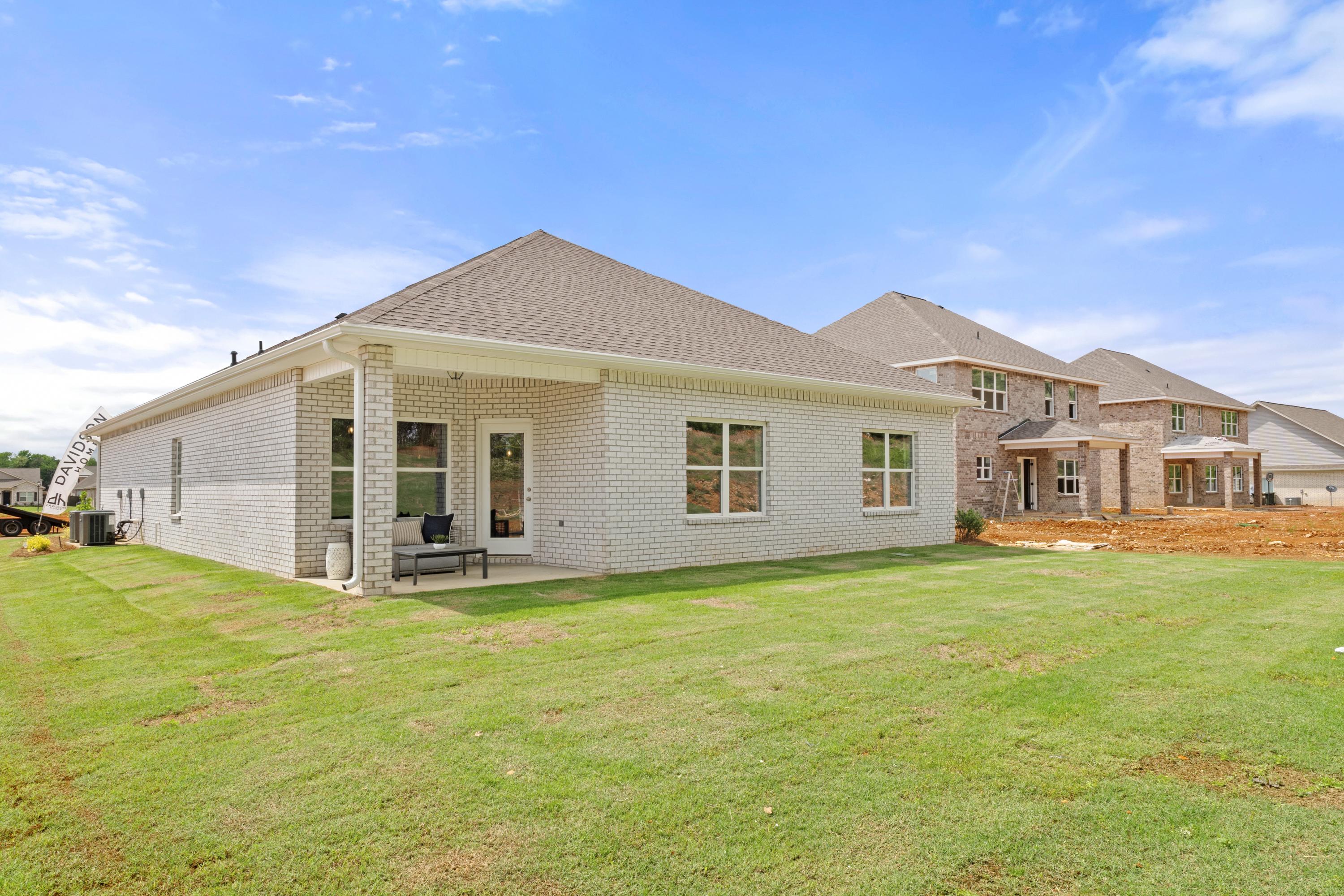 Brick home side exterior at Ivy Hills in Toney Alabama with covered patio, white columns, and green lawn