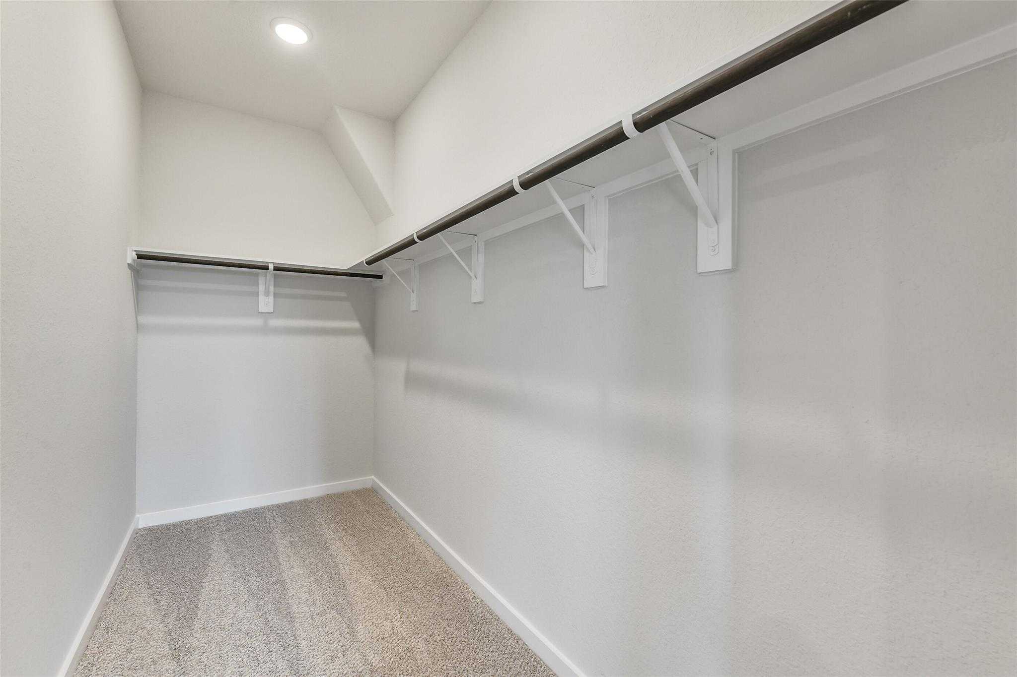 Spacious walk-in closet with double hanging rods and built-in shelves in master suite, Davidson Homes The Colorado G, Magnolia TX
