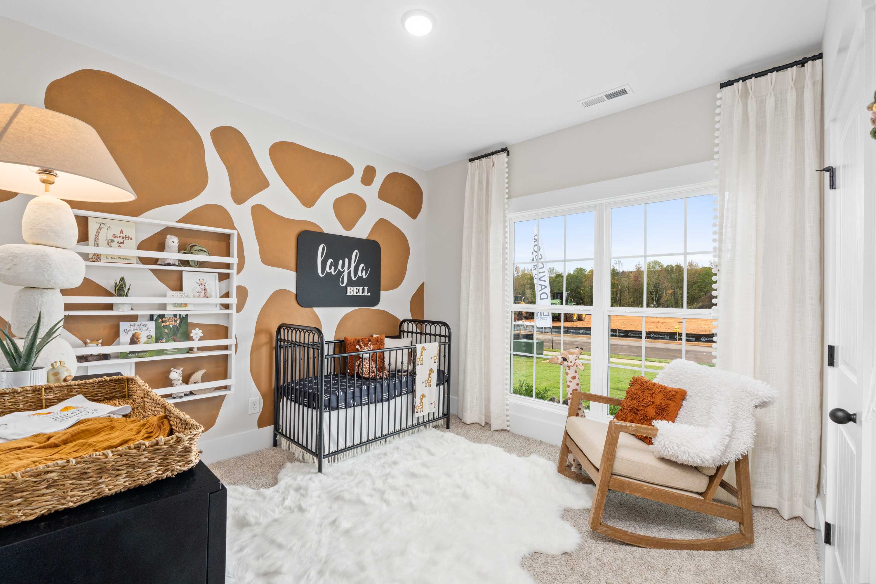 Giraffe-themed nursery at Spragins Cove in Huntsville AL by Davidson Homes with crib, rocking chair, rug and window view