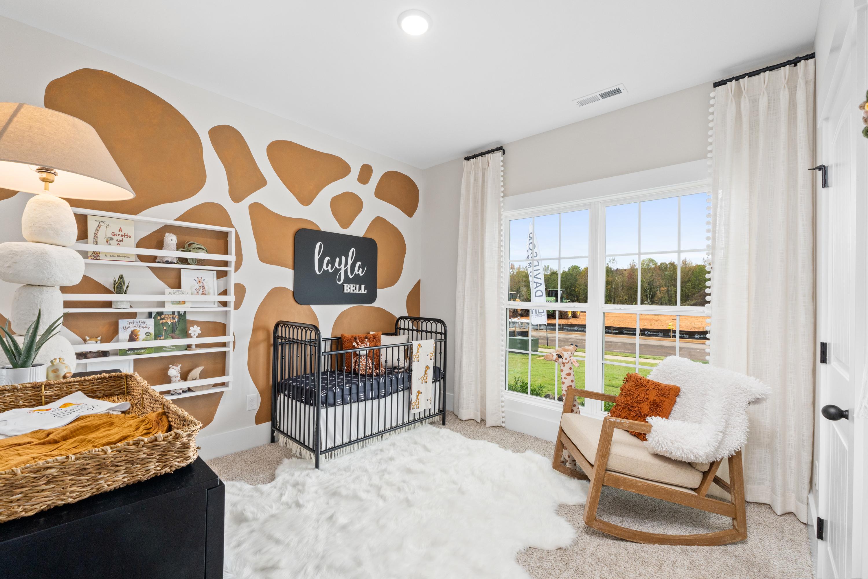 Giraffe-themed nursery at Spragins Cove in Huntsville AL by Davidson Homes with crib, rocking chair, rug and window view