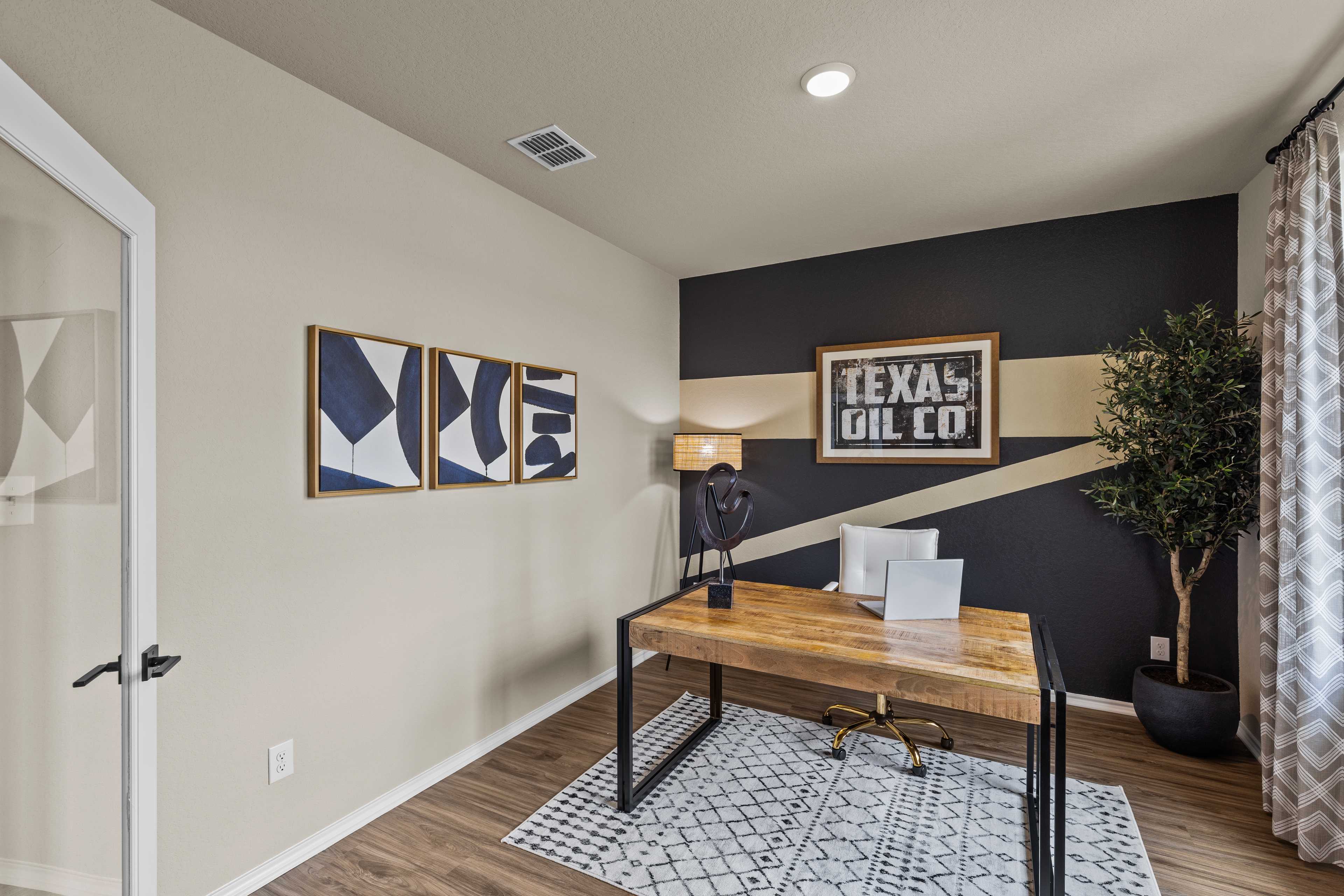 Contemporary home office in Bricewood San Antonio TX featuring wooden desk, Texas Oil Co wall sign, abstract art, and potted plant