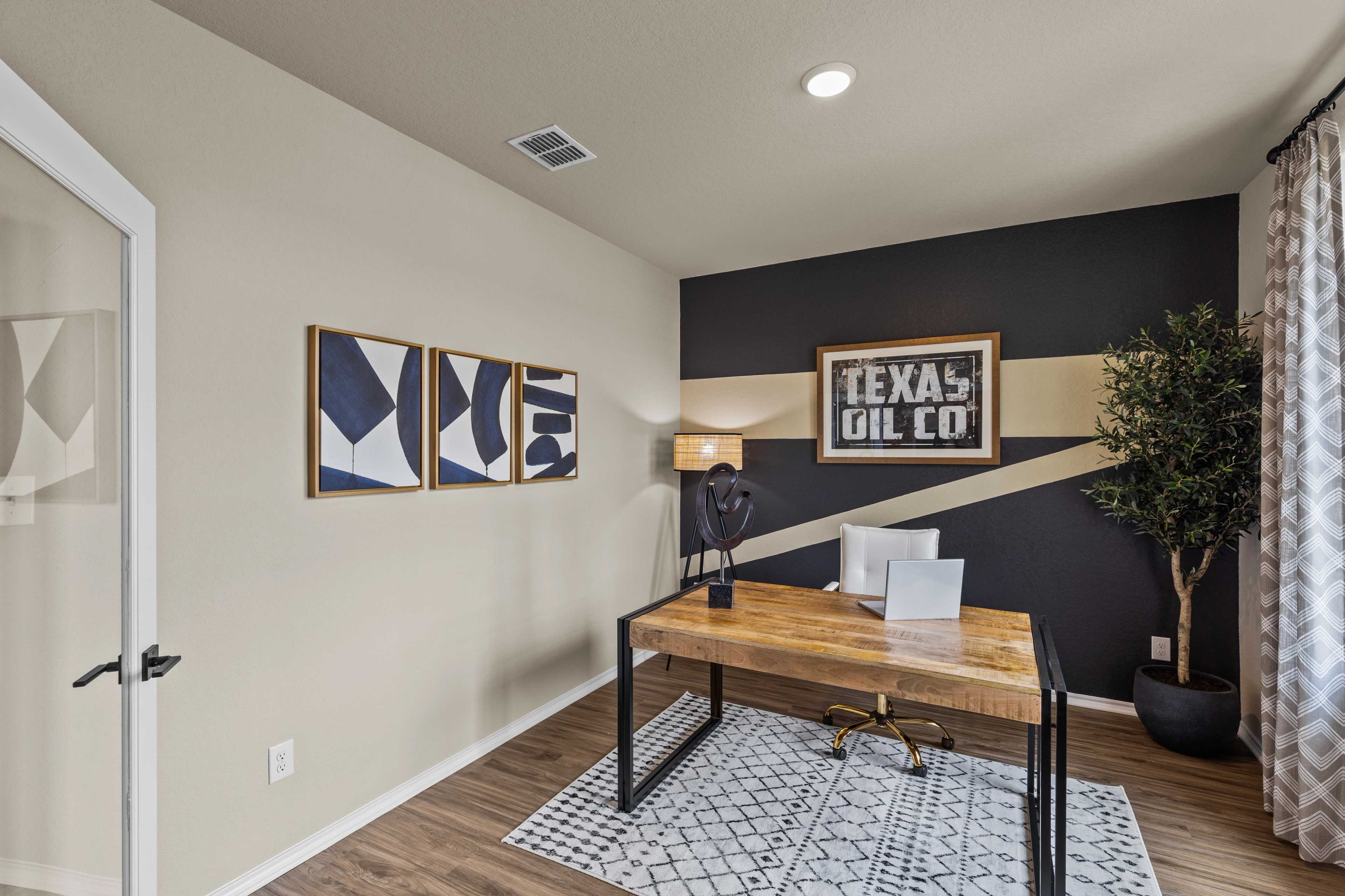Contemporary home office in Bricewood San Antonio TX featuring wooden desk, Texas Oil Co wall sign, abstract art, and potted plant