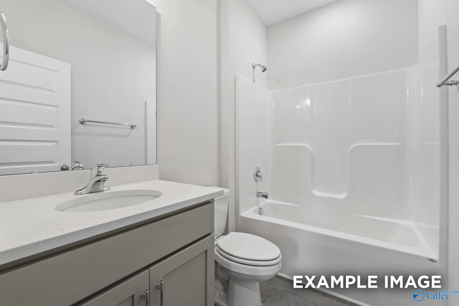 Bright bathroom with white tub-shower combo, gray vanity, and single sink in Davidson Homes The Montgomery, Athens, Alabama