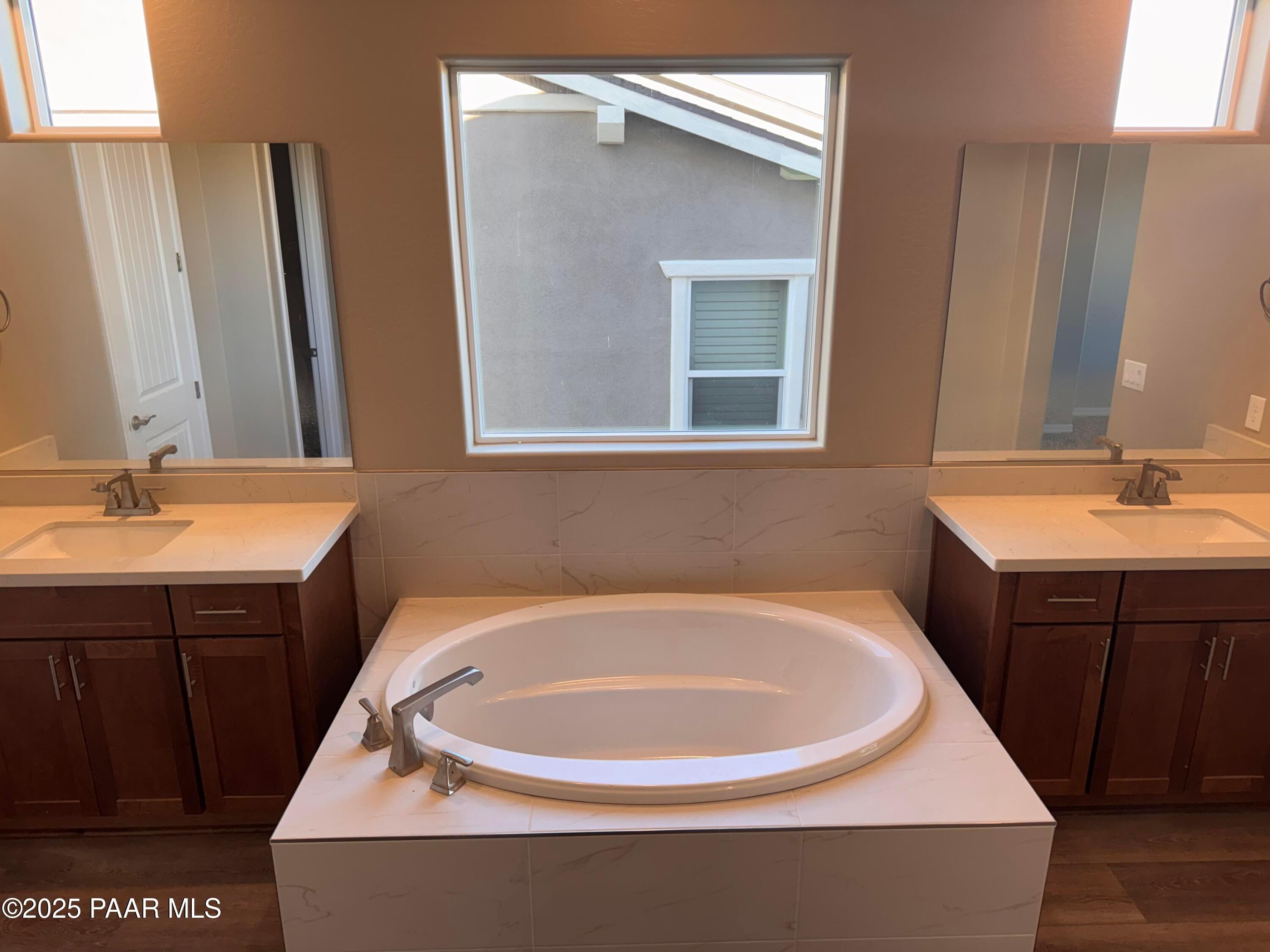 Luxurious master bath with dual quartz vanities, freestanding oval soaking tub, and large window in Davidson Homes The Sunrise II A, Prescott, AZ