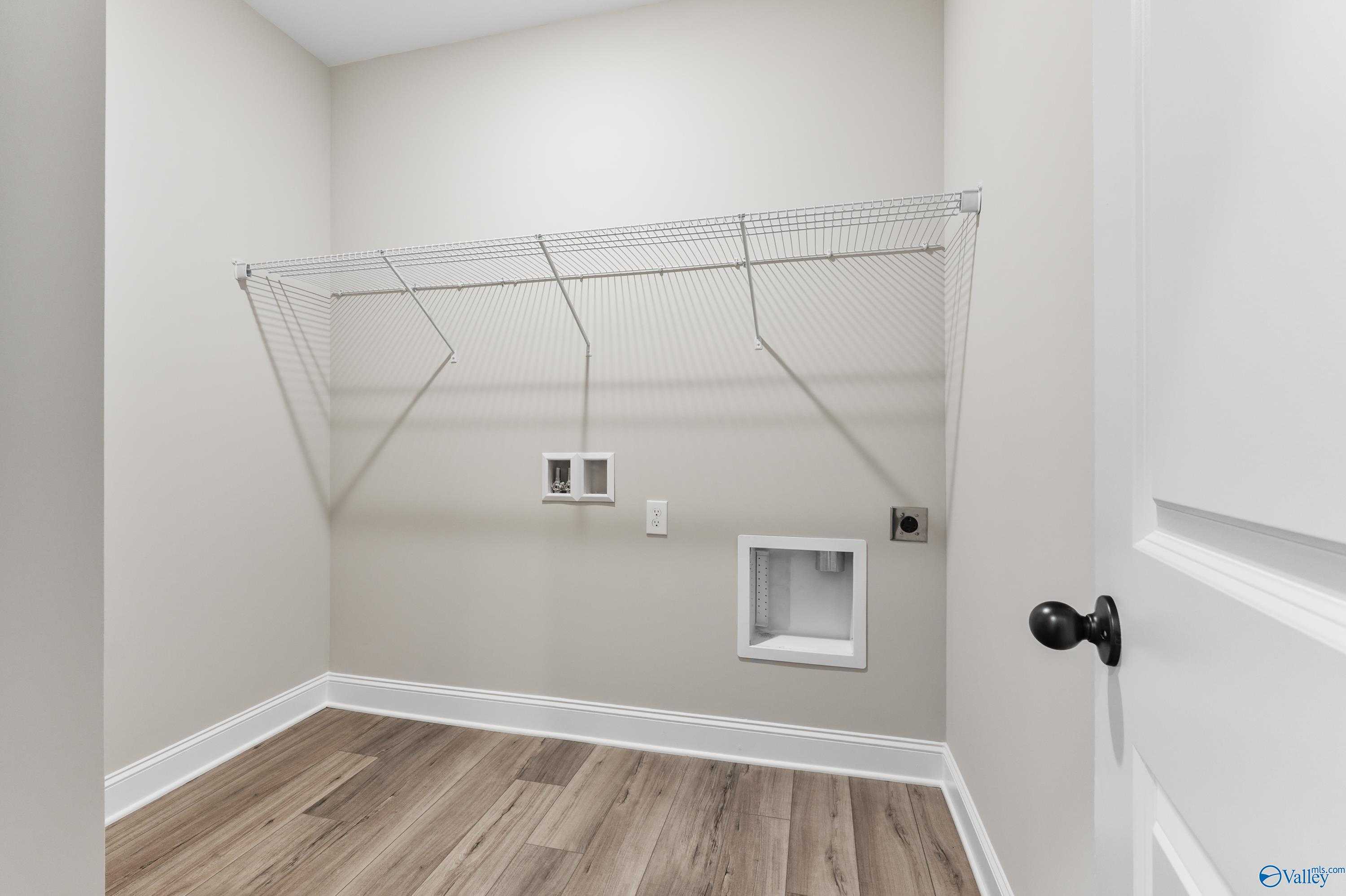 Spacious laundry room with wire shelving, washer/dryer hookups and hardwood floors in Davidson Homes The Daphne C, Hazel Green, Alabama