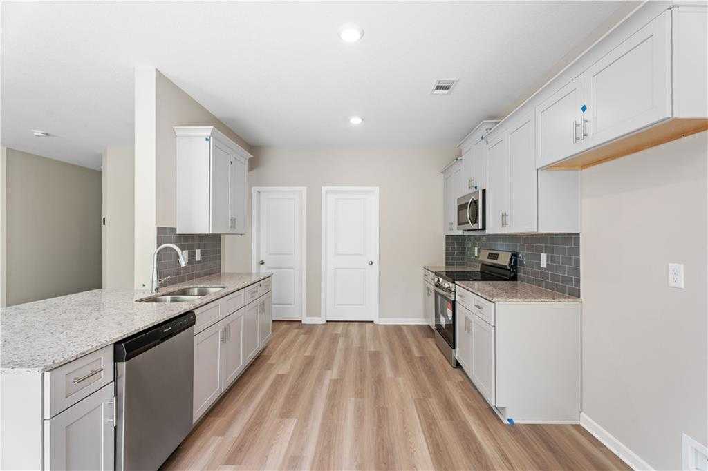 Modern white shaker kitchen with granite counters, stainless appliances, subway tile backsplash in The Bartlett plan, Phenix City AL