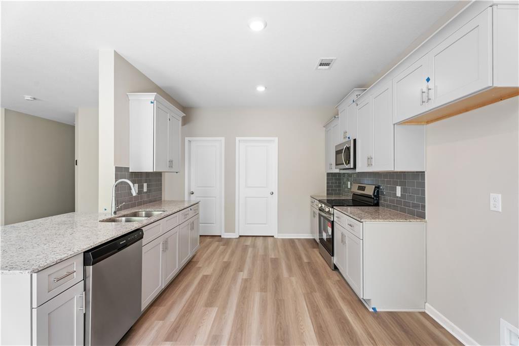 Modern white shaker kitchen with granite counters, stainless appliances, subway tile backsplash in The Bartlett plan, Phenix City AL