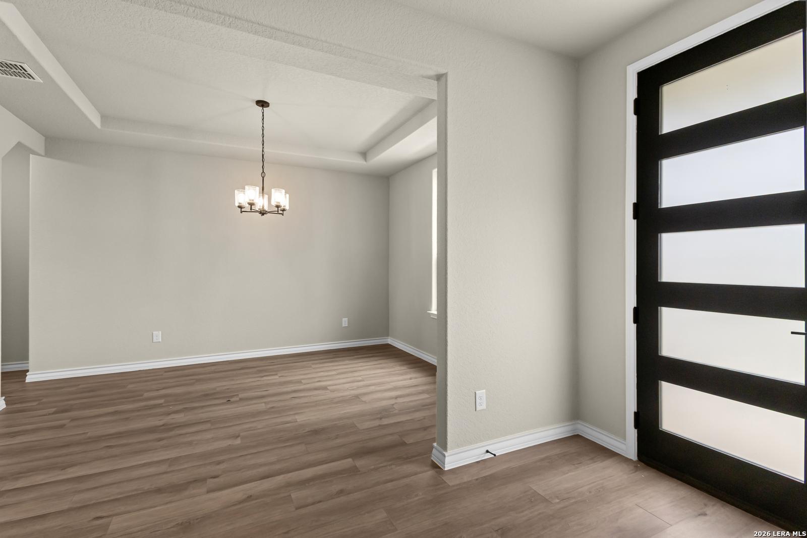 Formal dining room with tray ceiling and modern chandelier in The Danbury H model home at The Reserve at Potranco Oaks.