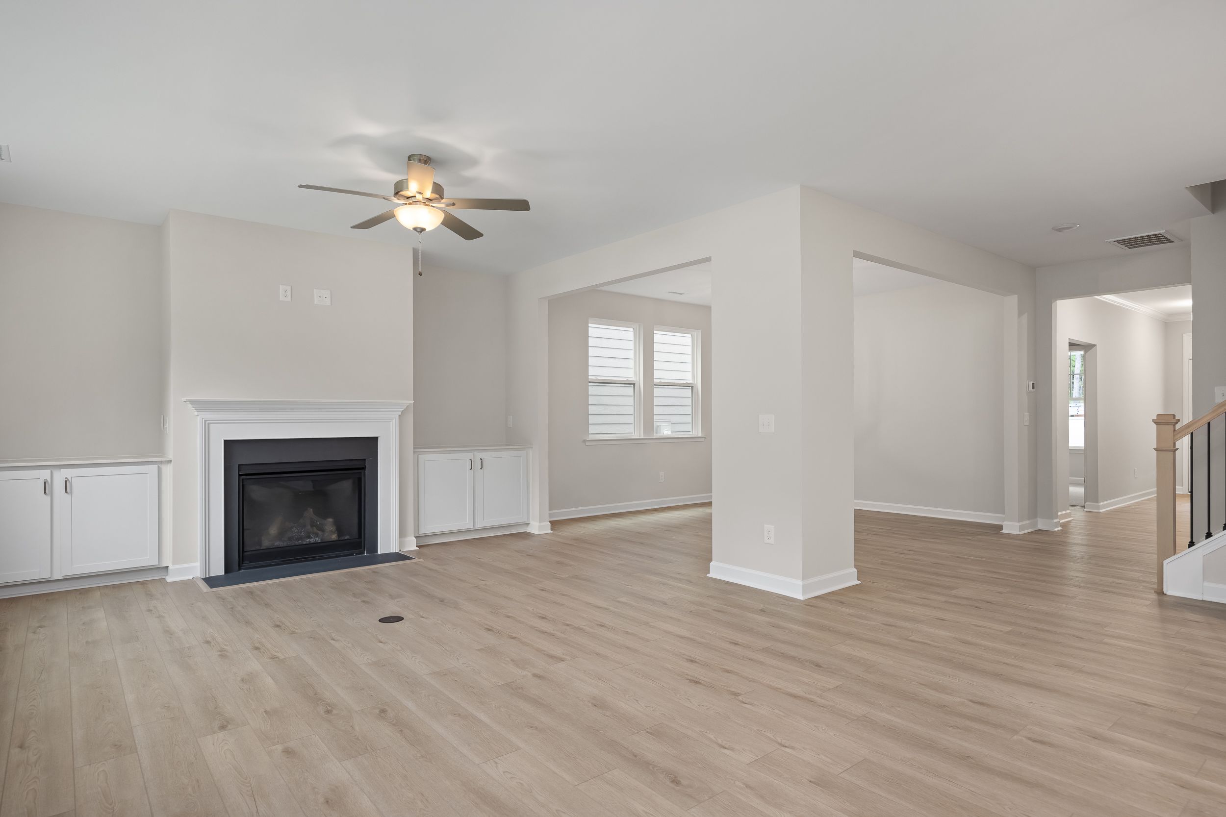 Spacious open-concept family room in The Beech A featuring gas fireplace, ceiling fan, hardwood floors
